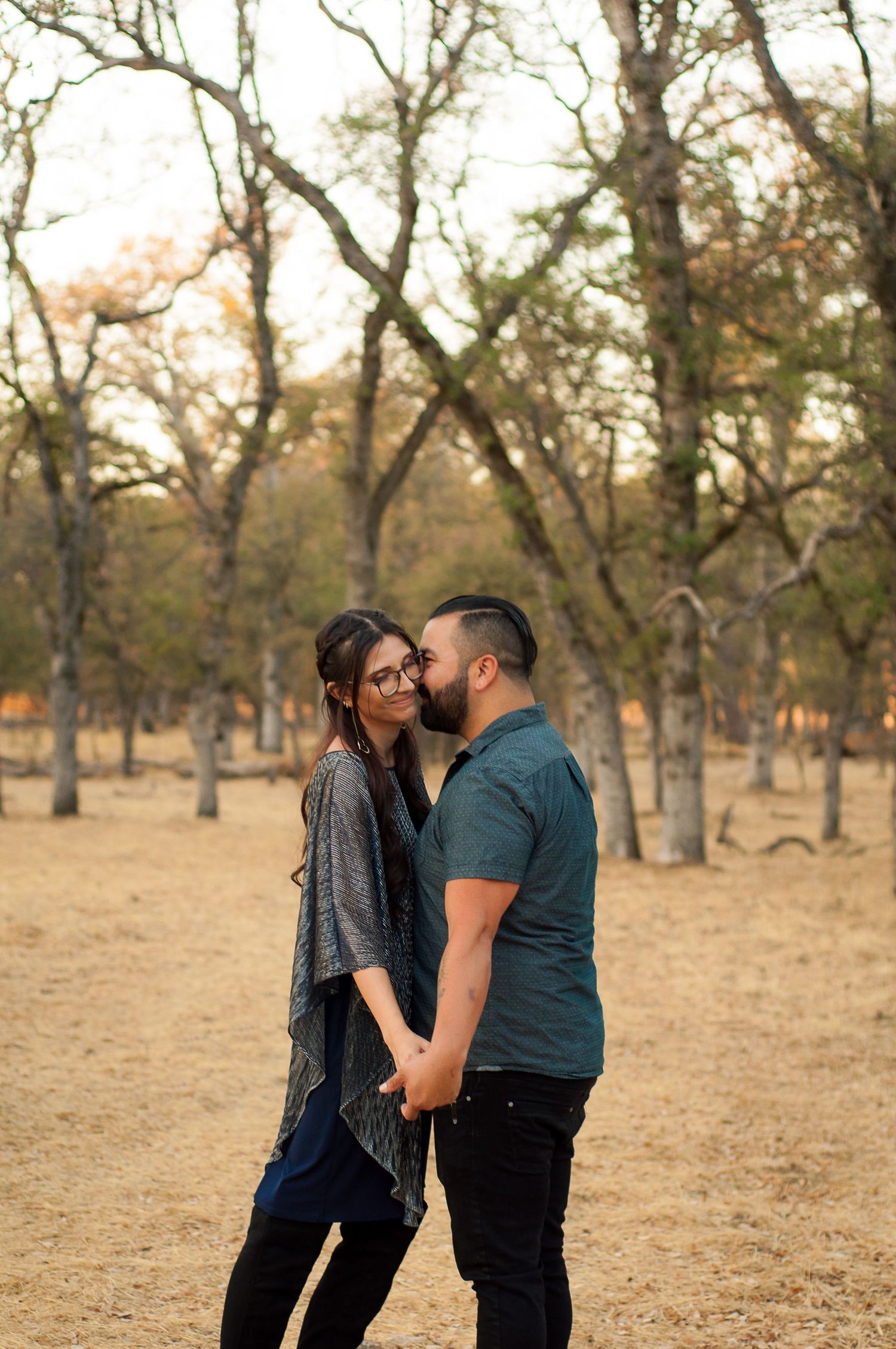 Couple embracing among the trees during a candid outdoor portrait session.