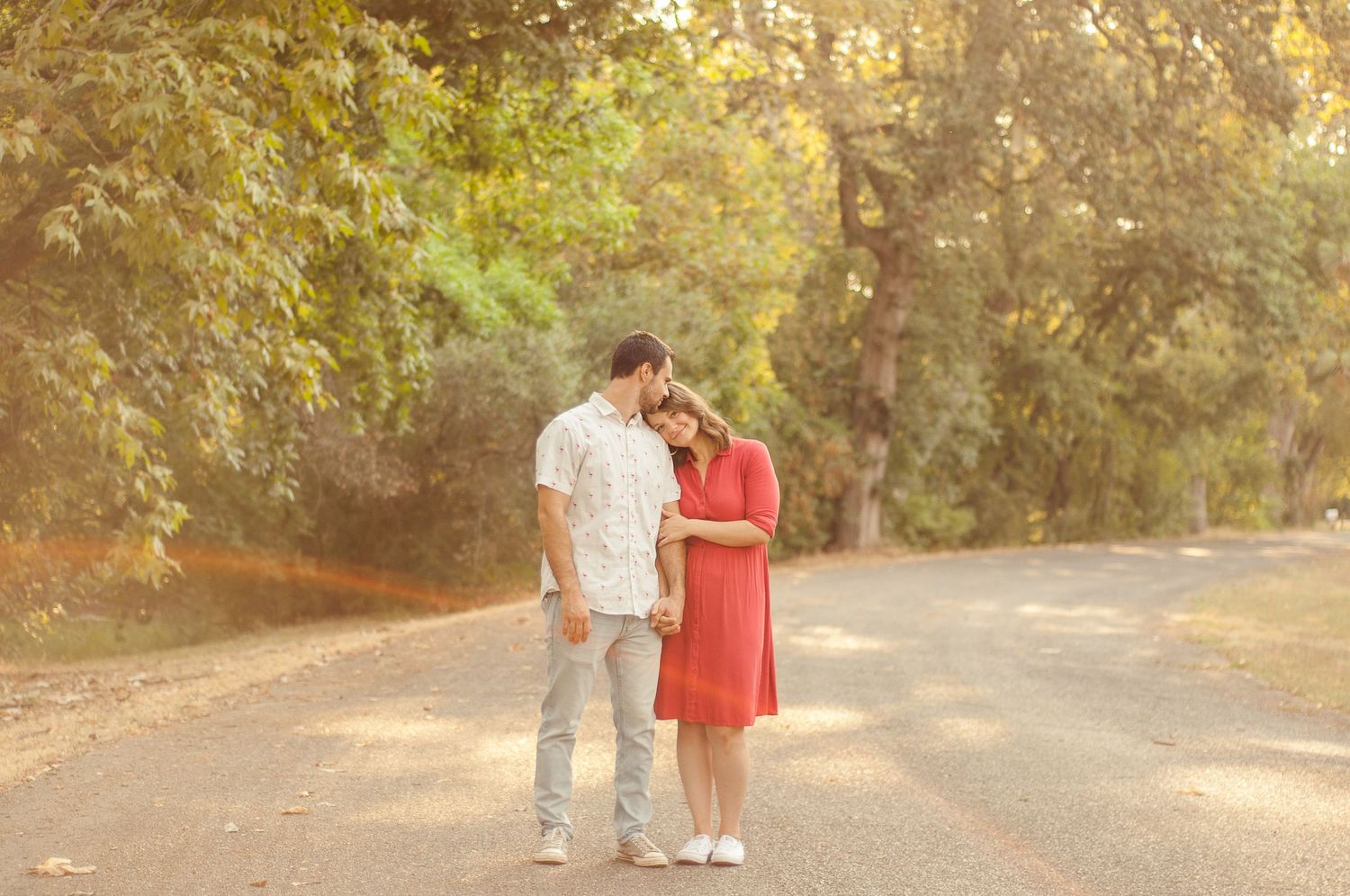 Couple sharing a quiet moment together on a warm, sunlit road during an outdoor portrait session.