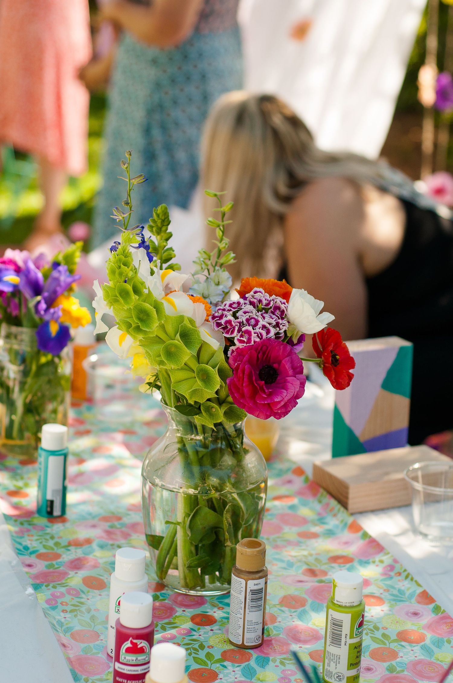 Colorful flowers and painting supplies arranged for an outdoor craft gathering.