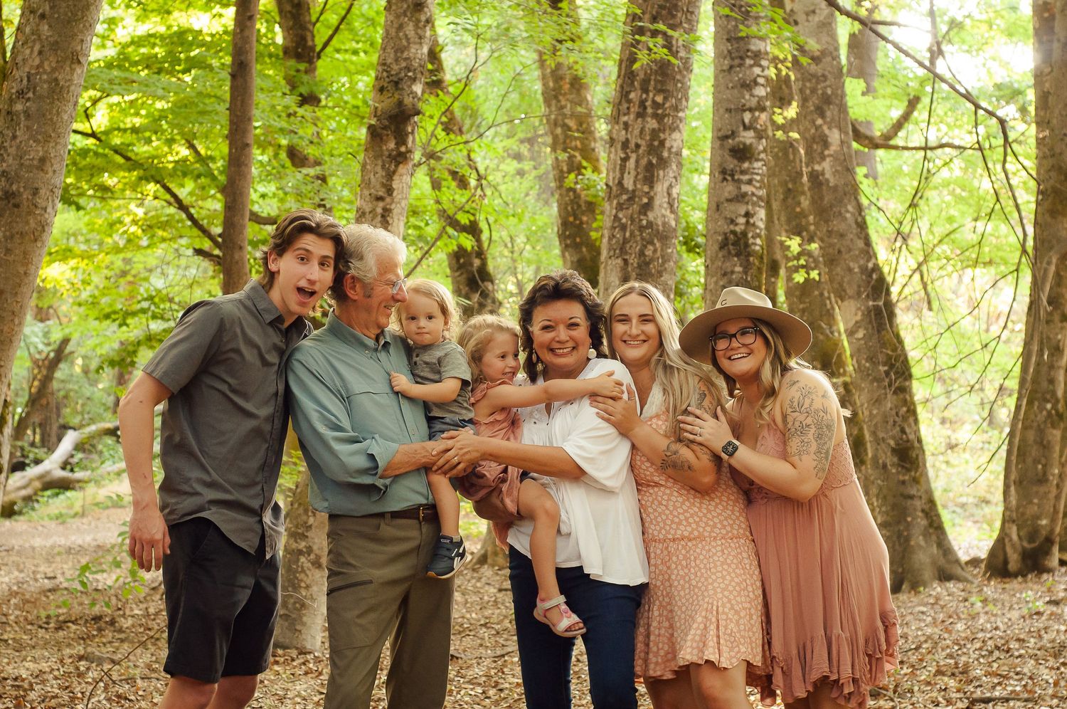 Multigenerational family smiling and embracing together during a wooded portrait session.