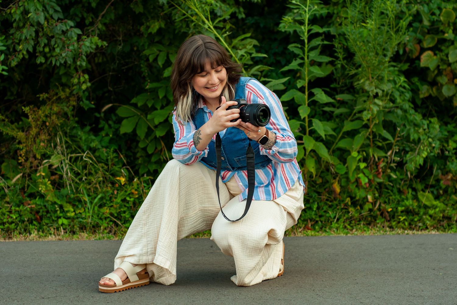 Marie Murray crouching with her camera during an outdoor branding portrait session.