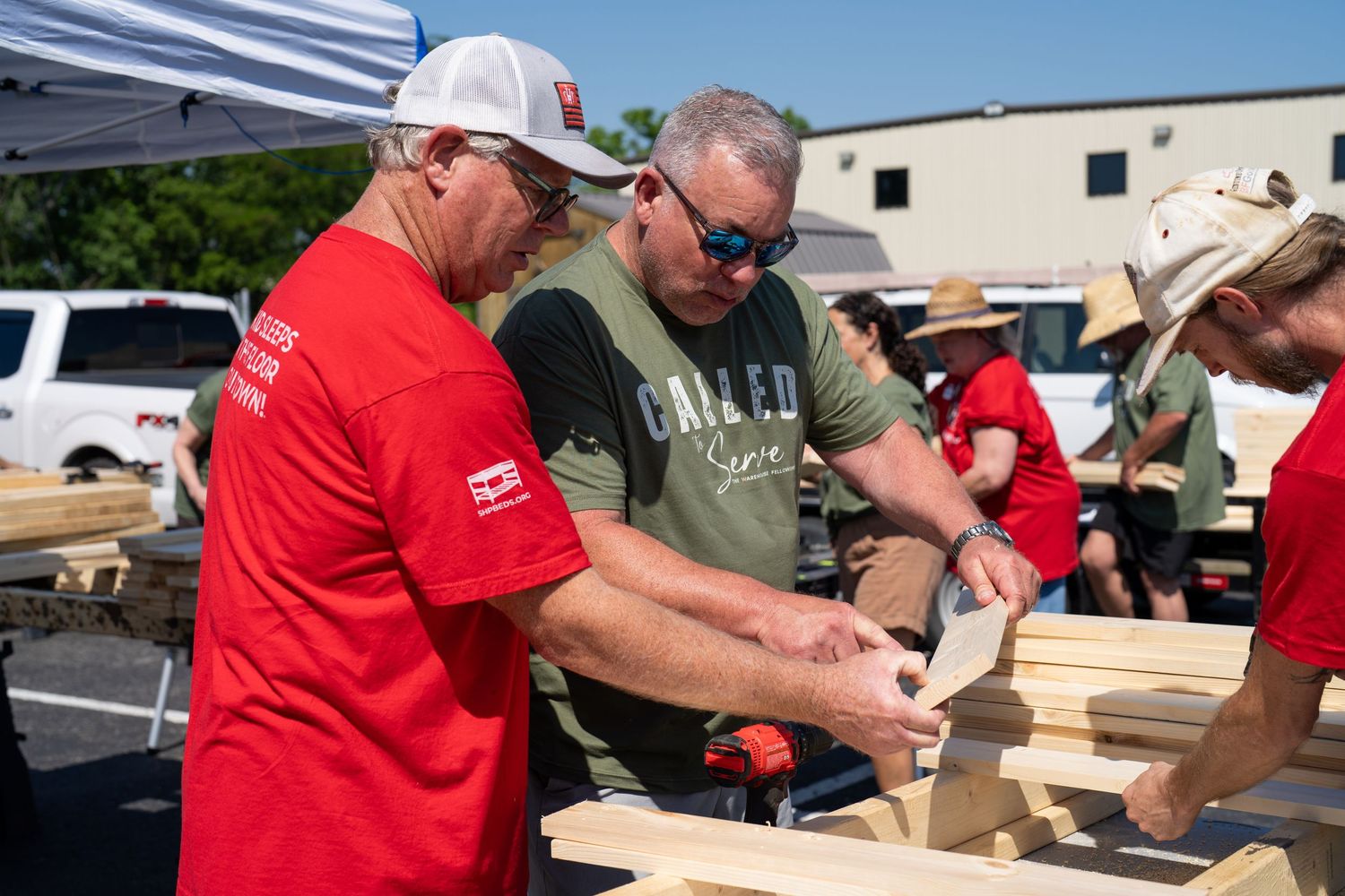 Volunteers assembling wooden boards together during an outdoor community service project.