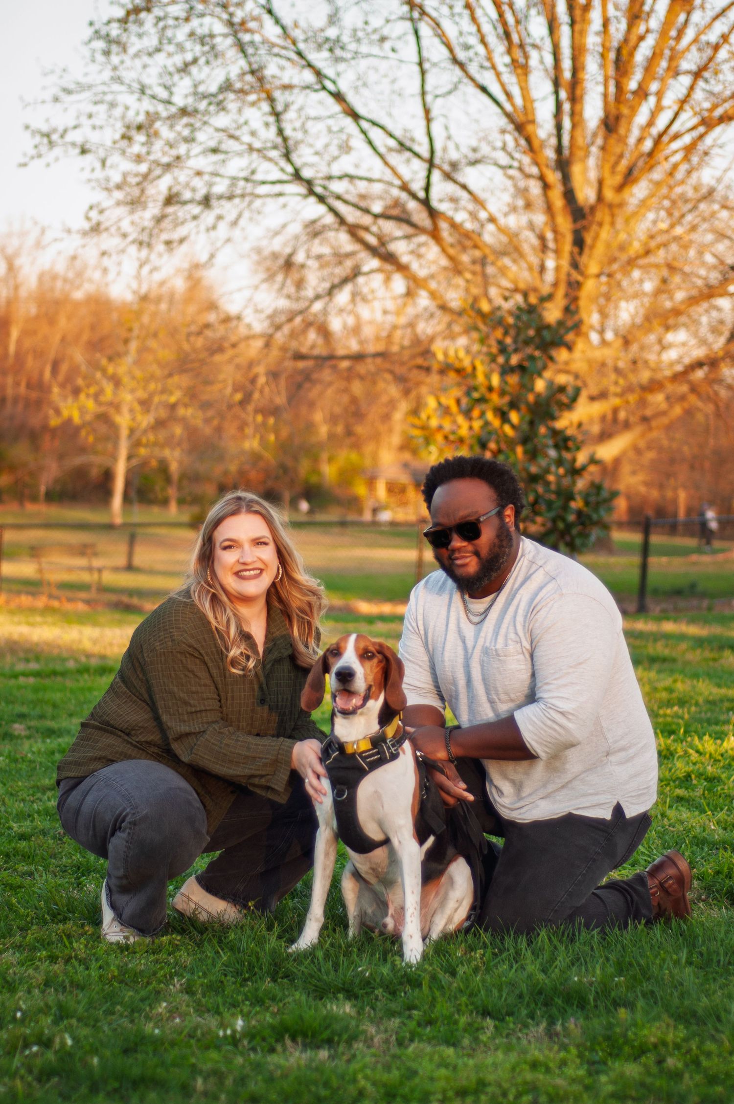 Couple interacting with their dog during a relaxed outdoor portrait session at sunset.
