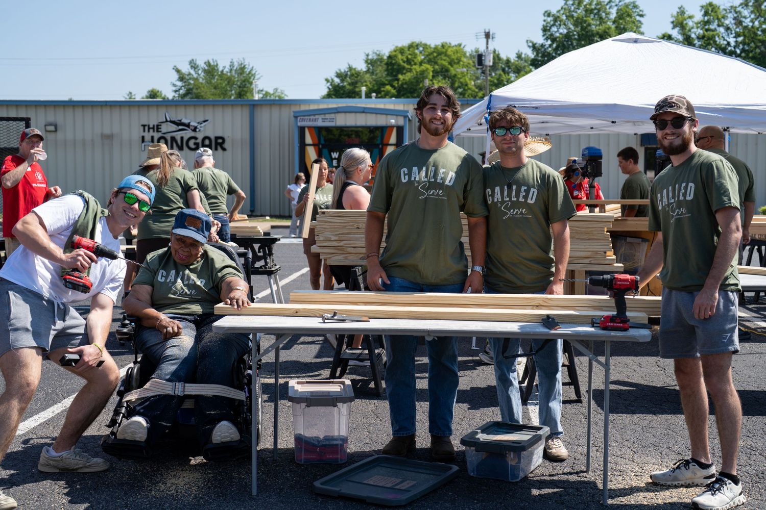 Volunteers from The Warehouse Fellowship working together at tables during an outdoor community service project.