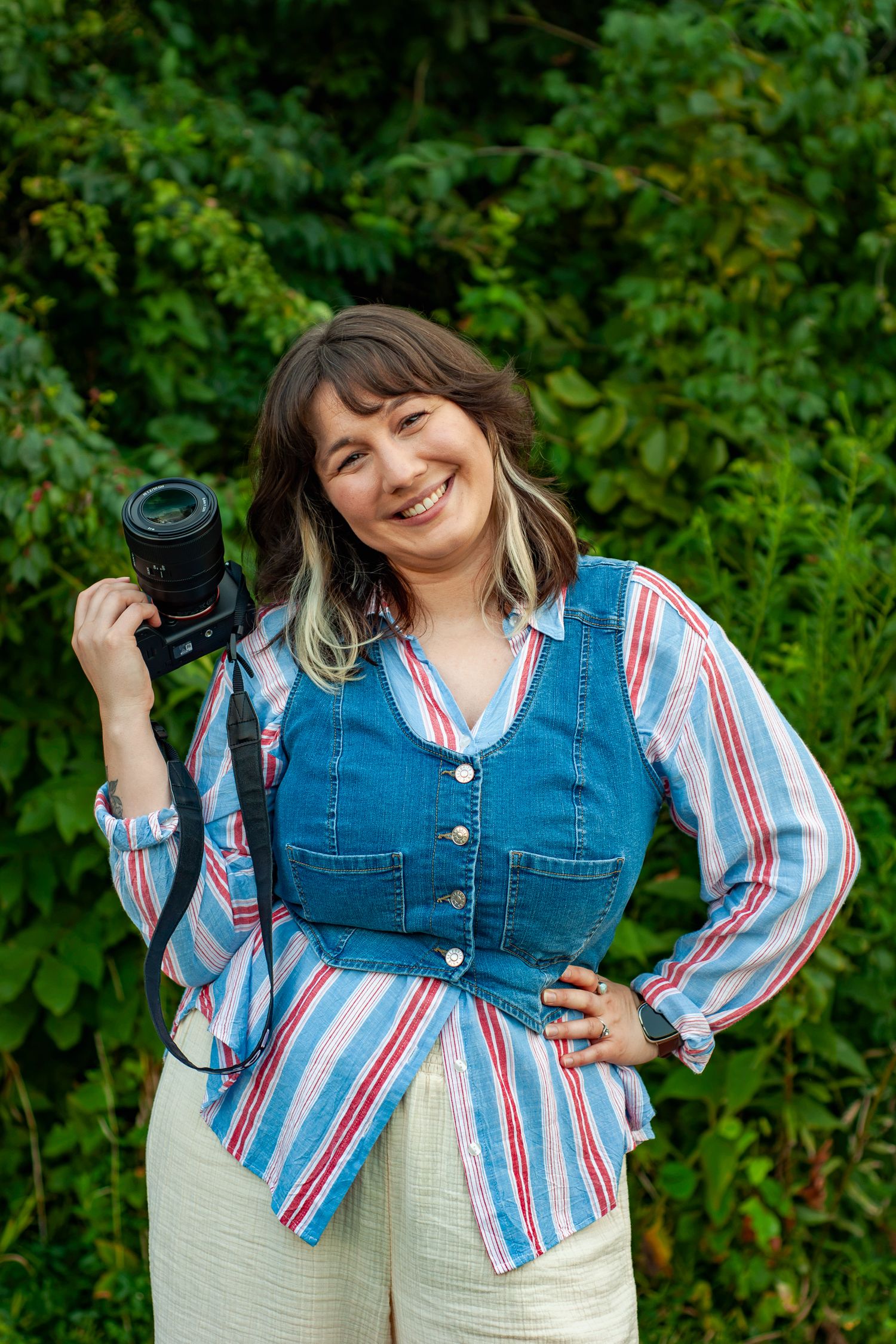 Marie Murray smiling with her camera during an outdoor branding portrait session at sunset.