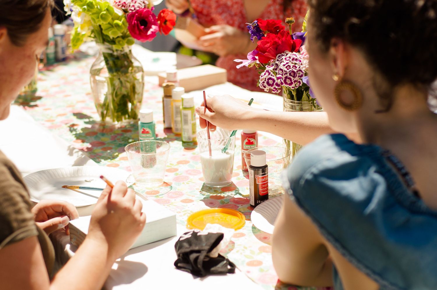Guests painting crafts together at a colorful outdoor gathering.