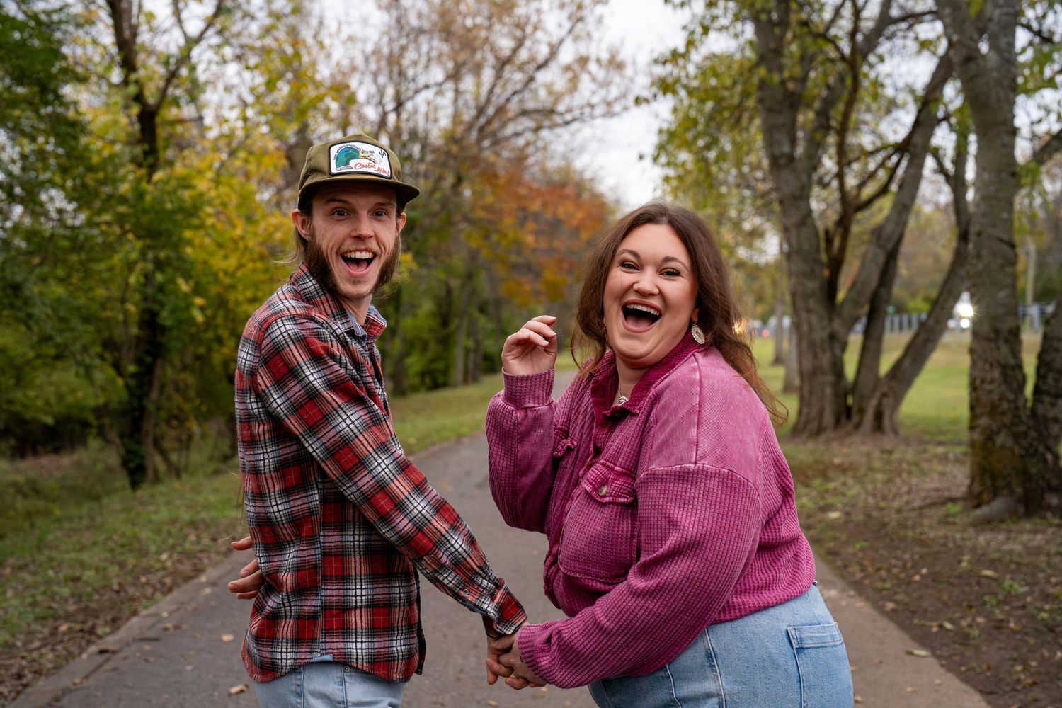 Couple laughing together during a playful fall portrait session.