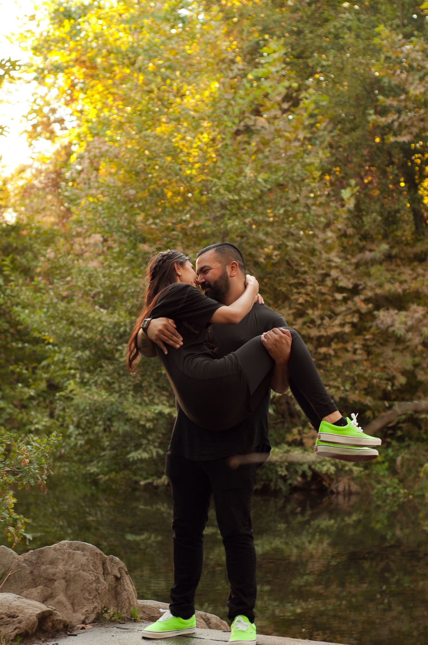 Couple laughing together during an outdoor portrait session beside a wooded creek.