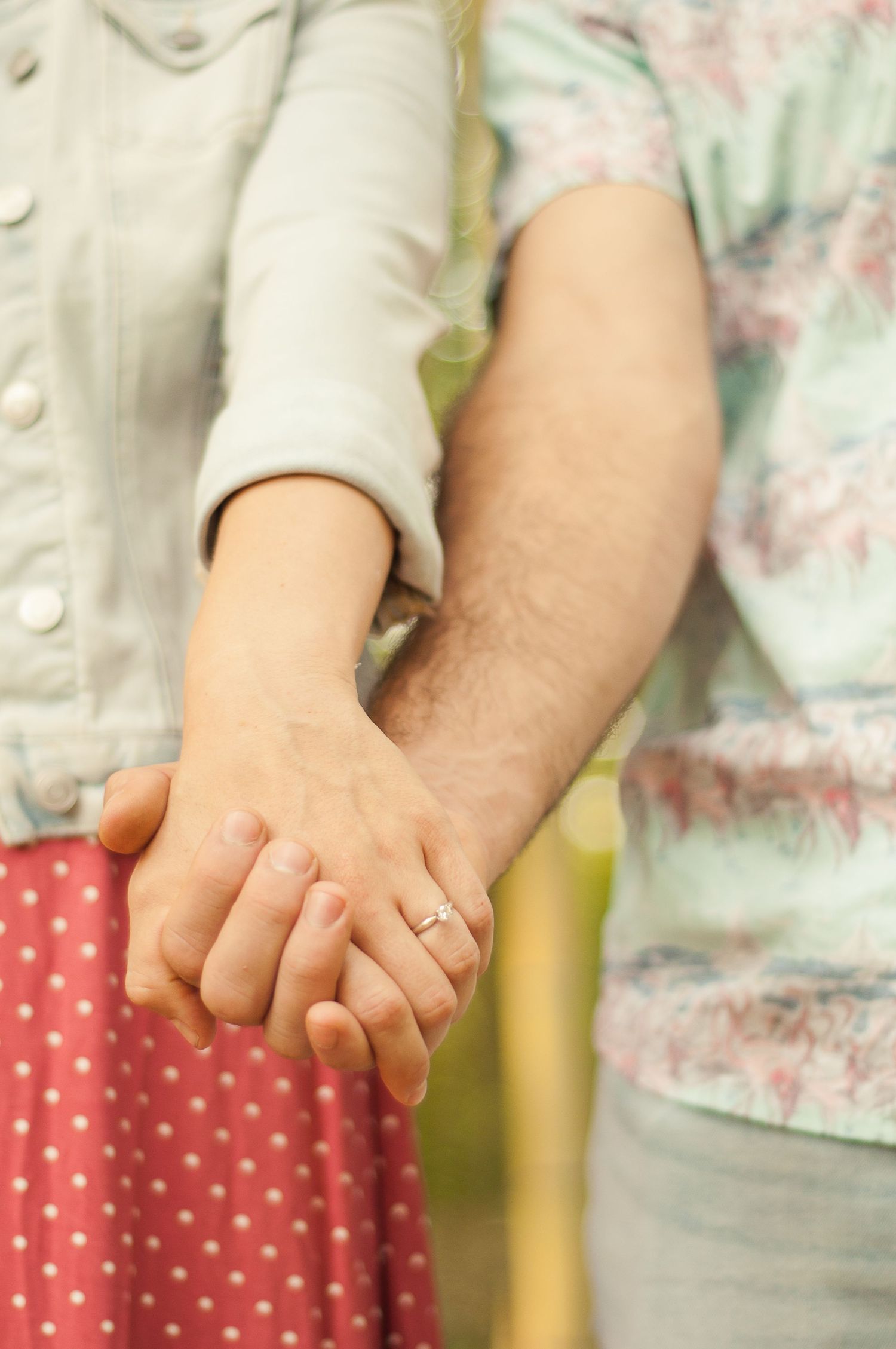 Close-up of a couple holding hands during an outdoor portrait session showing off engagement ring.