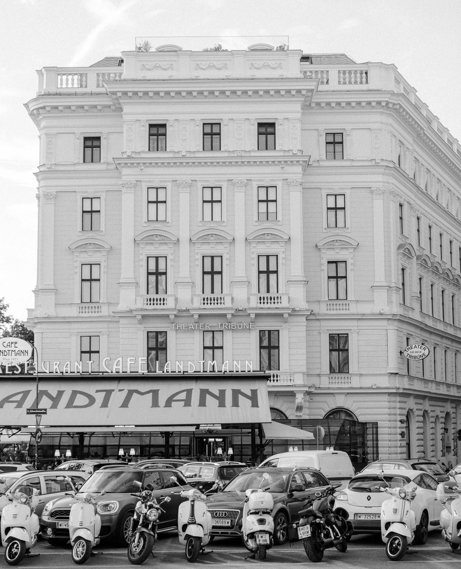 black and white image of Cafe Landtmann in Vienna, Austria with mopeds parked on the street