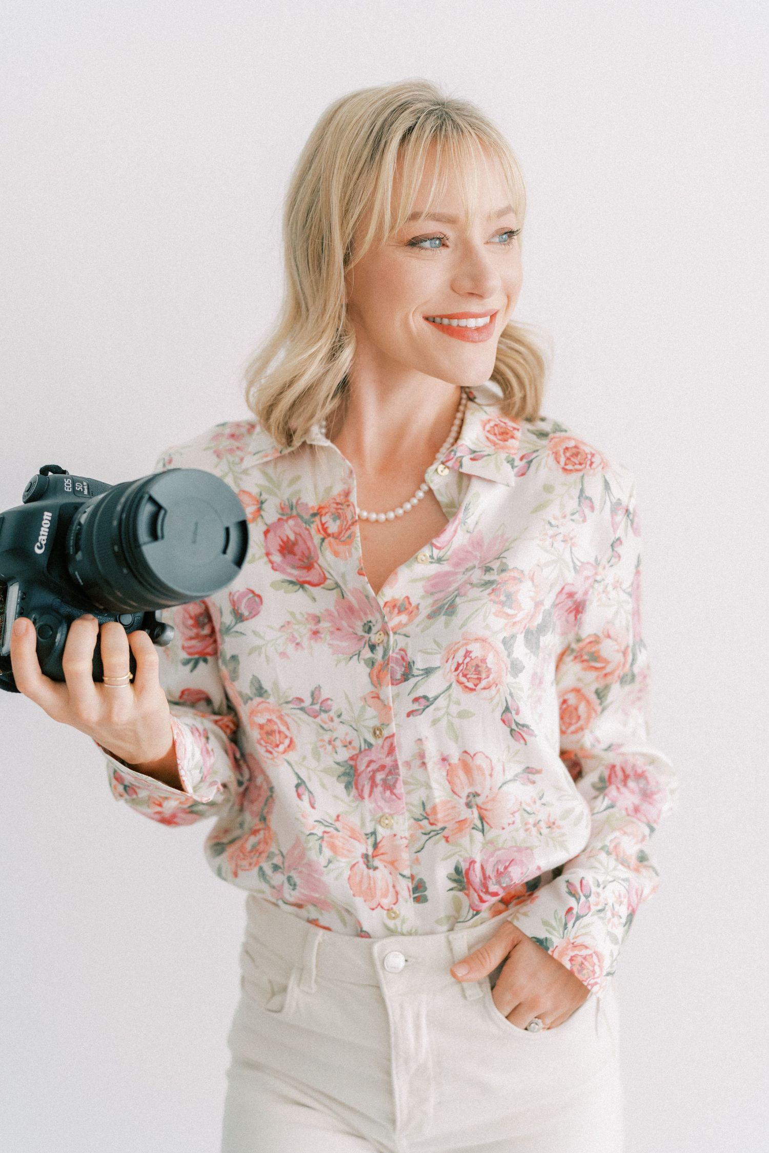 Image of Alyssa Greif holding her camera in a natural light studio smiling