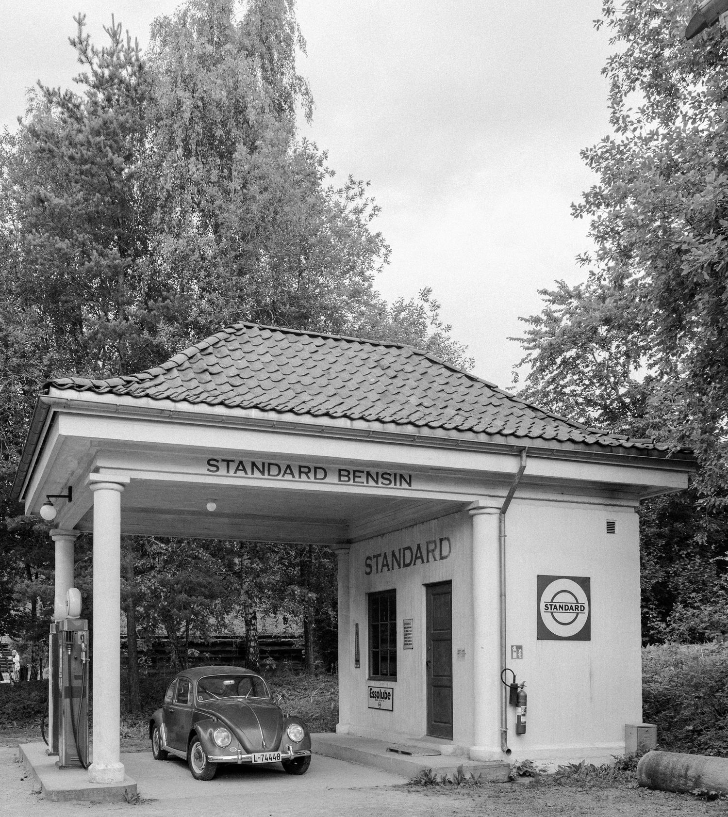 Black and white image of a car underneath a vintage gas station in Norway
