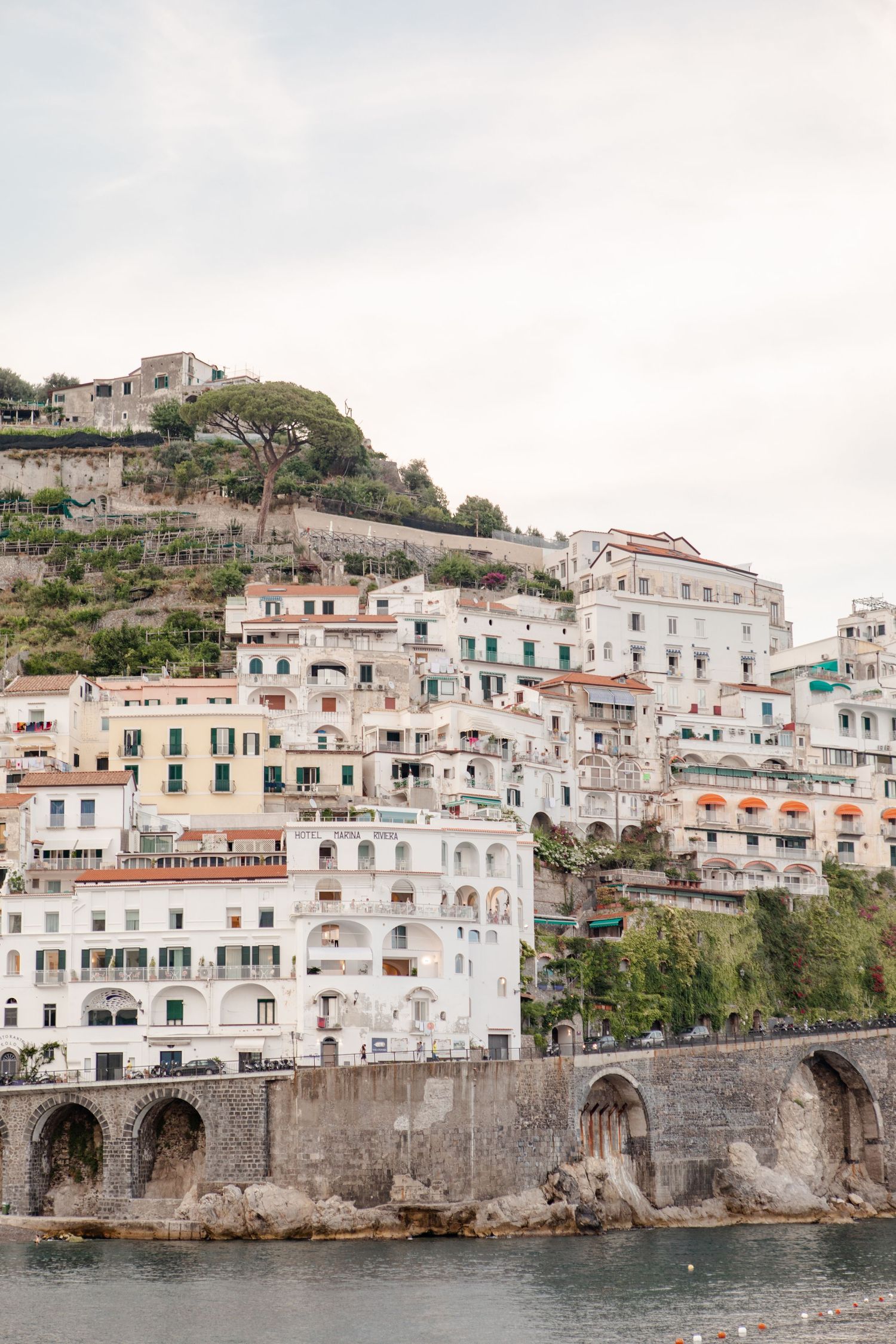 Muted color image of Amalfi coast with buildings ascending a hill near the ocean