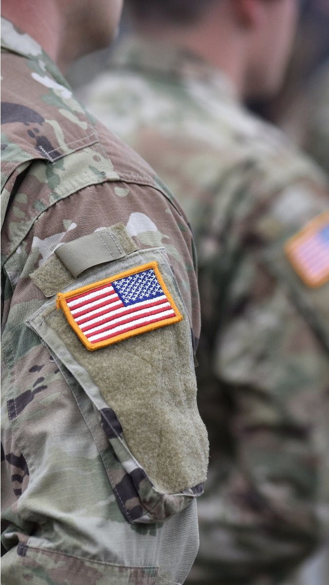 Military members in their OCP Uniforms with the American Patch on their right shoulder while standing in formation.