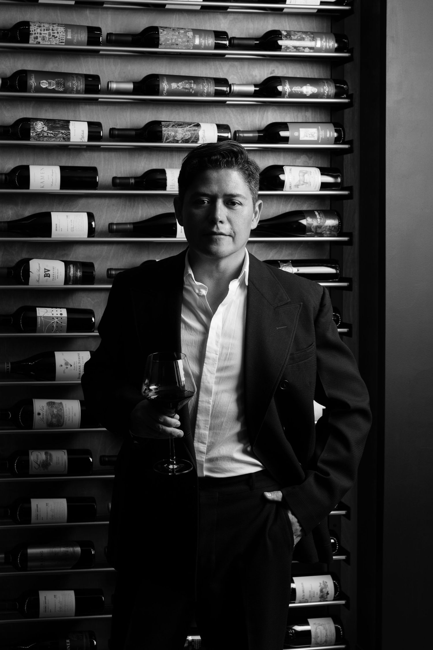 Man in suit standing in front of wine display. Image taken by veteran photographer and Two Black Ravens founder Adam