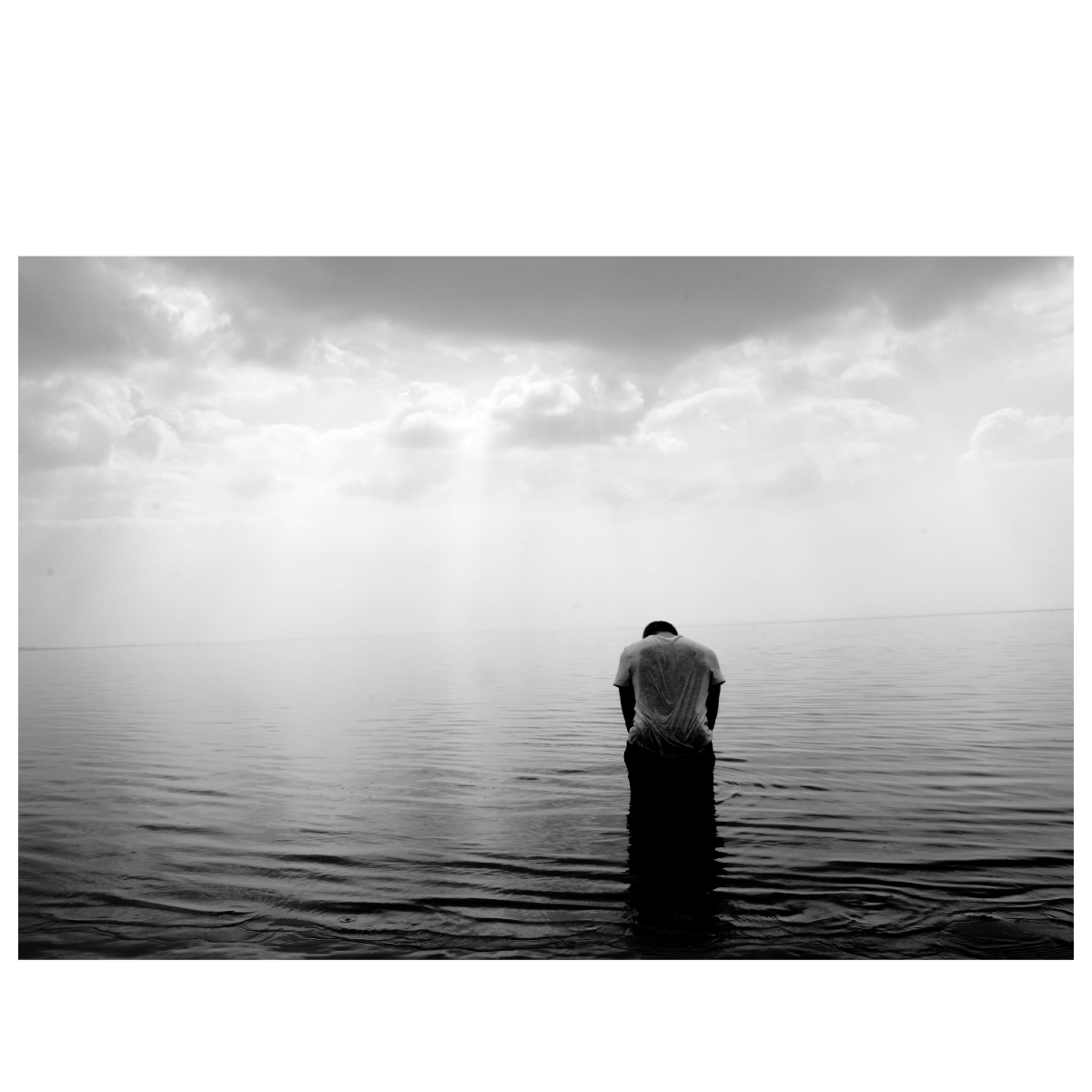 Black and White image of Man in water with a mood depicting depression or overwhelmed.