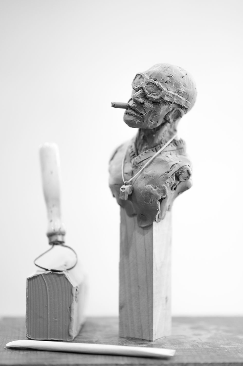 Clay sculpture of mans head wearing googles smoking a cigar by veteran artist and instructor Jessie Schwartz