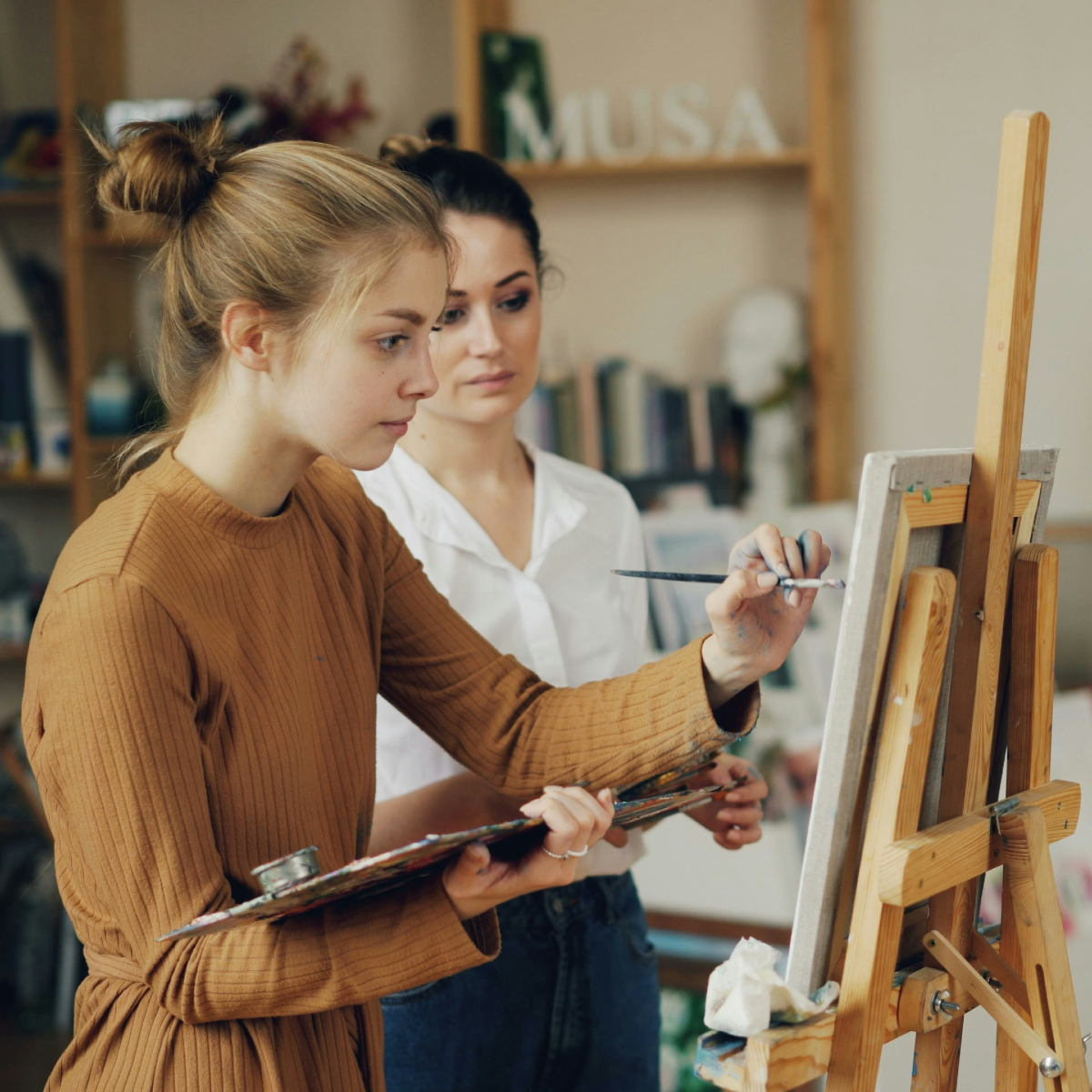 Veteran female artist painting with instructor providing guidance