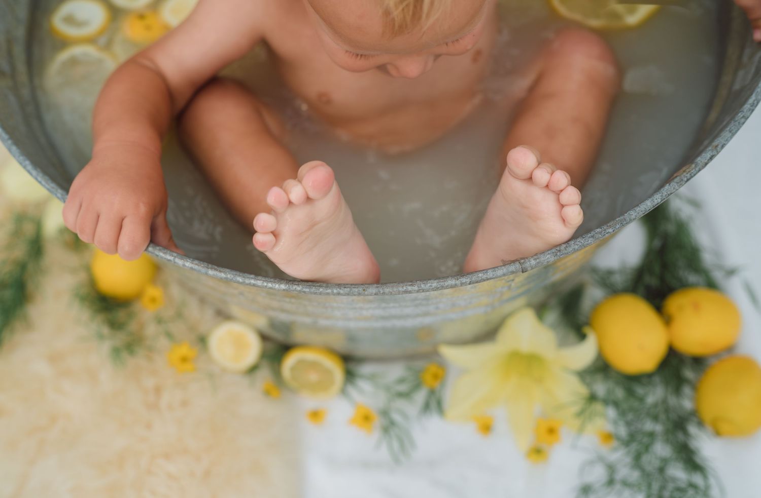 Someone squeezes fresh lemon juice into a bowl with their hands against a white and yellow background.