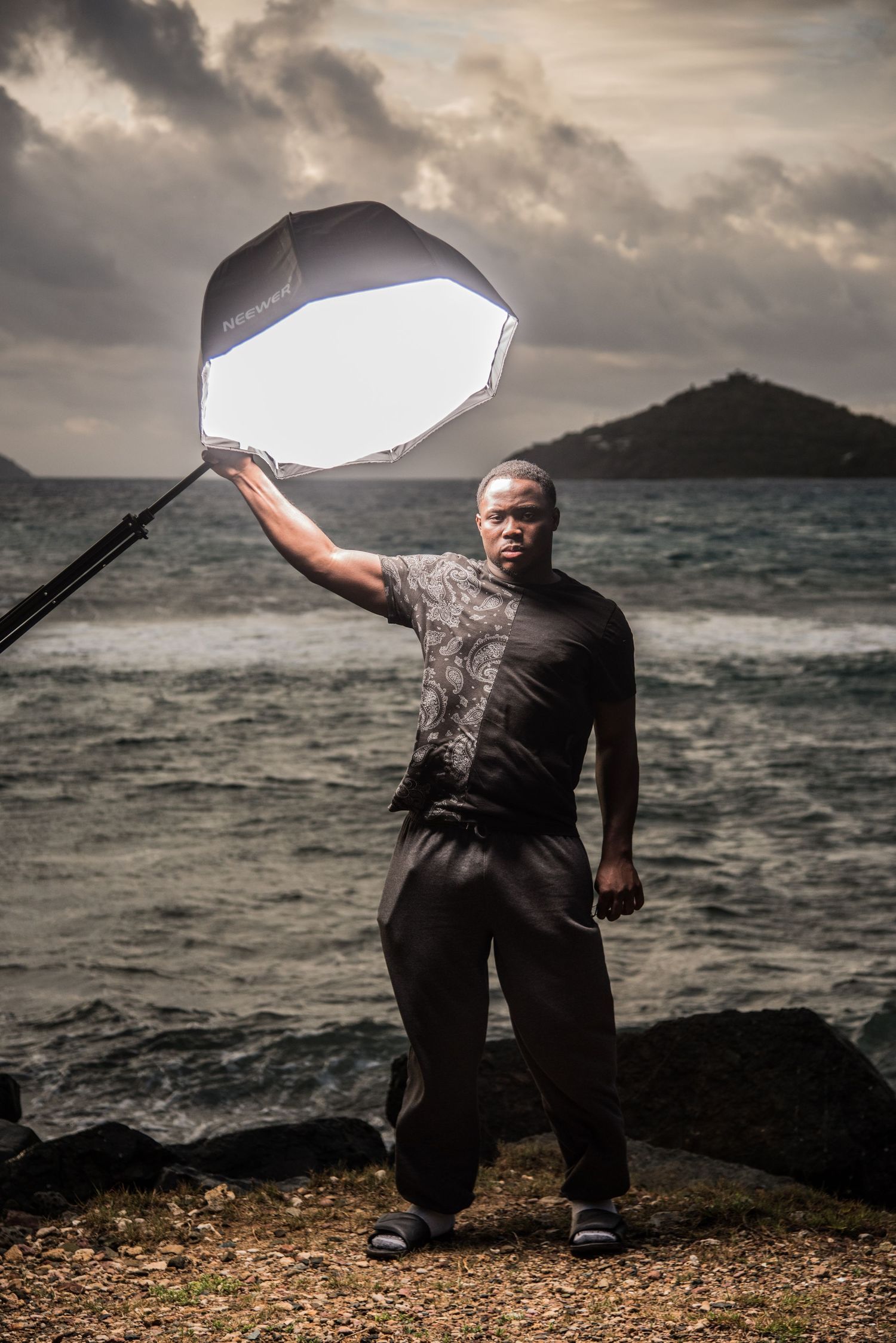 Dramatic outdoor photoshoot with reflector against stormy ocean backdrop.