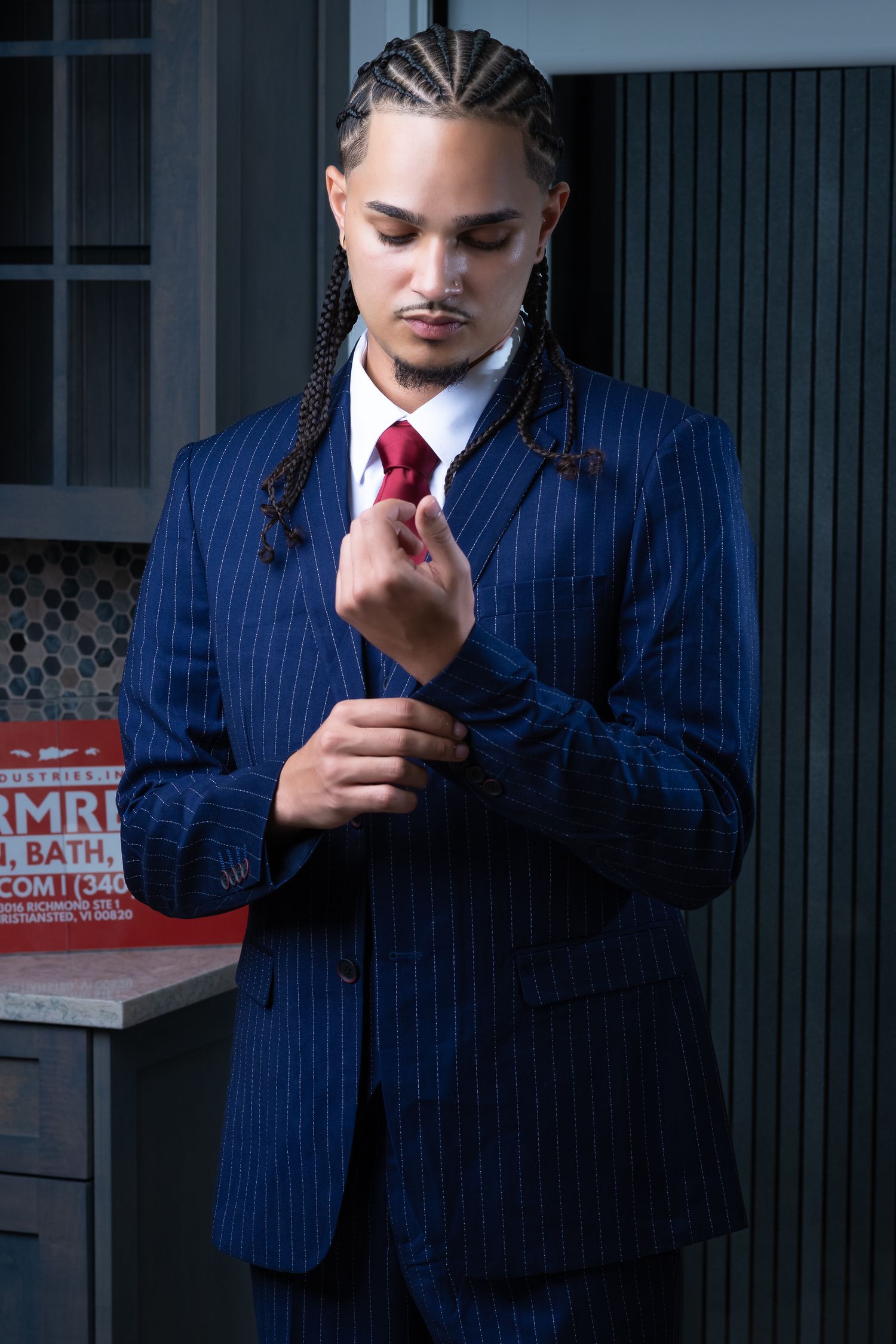 Stylish business portrait featuring a navy pinstriped suit and red tie in moody lighting.