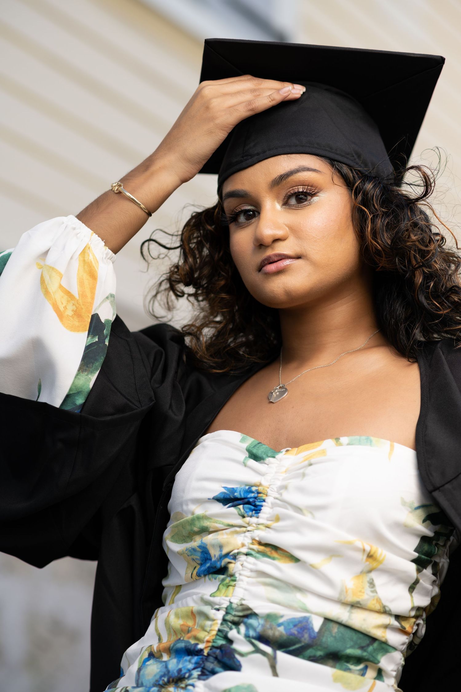 Fashion portrait series featuring a floral dress and black graduation cap styled in multiple artistic poses.