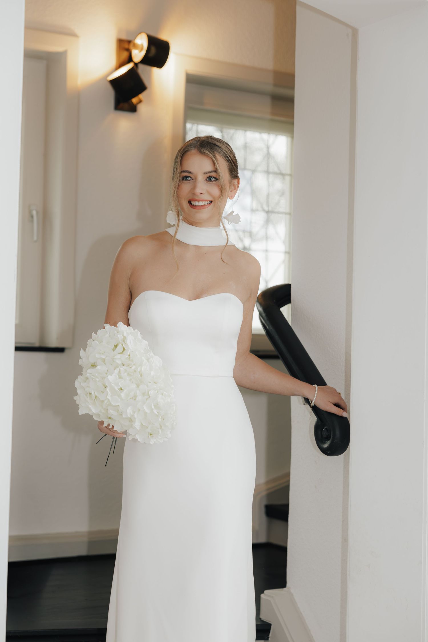 Braut im Türrahmen mit Bouquet, elegantes Fine Art Editorial bei Beckum