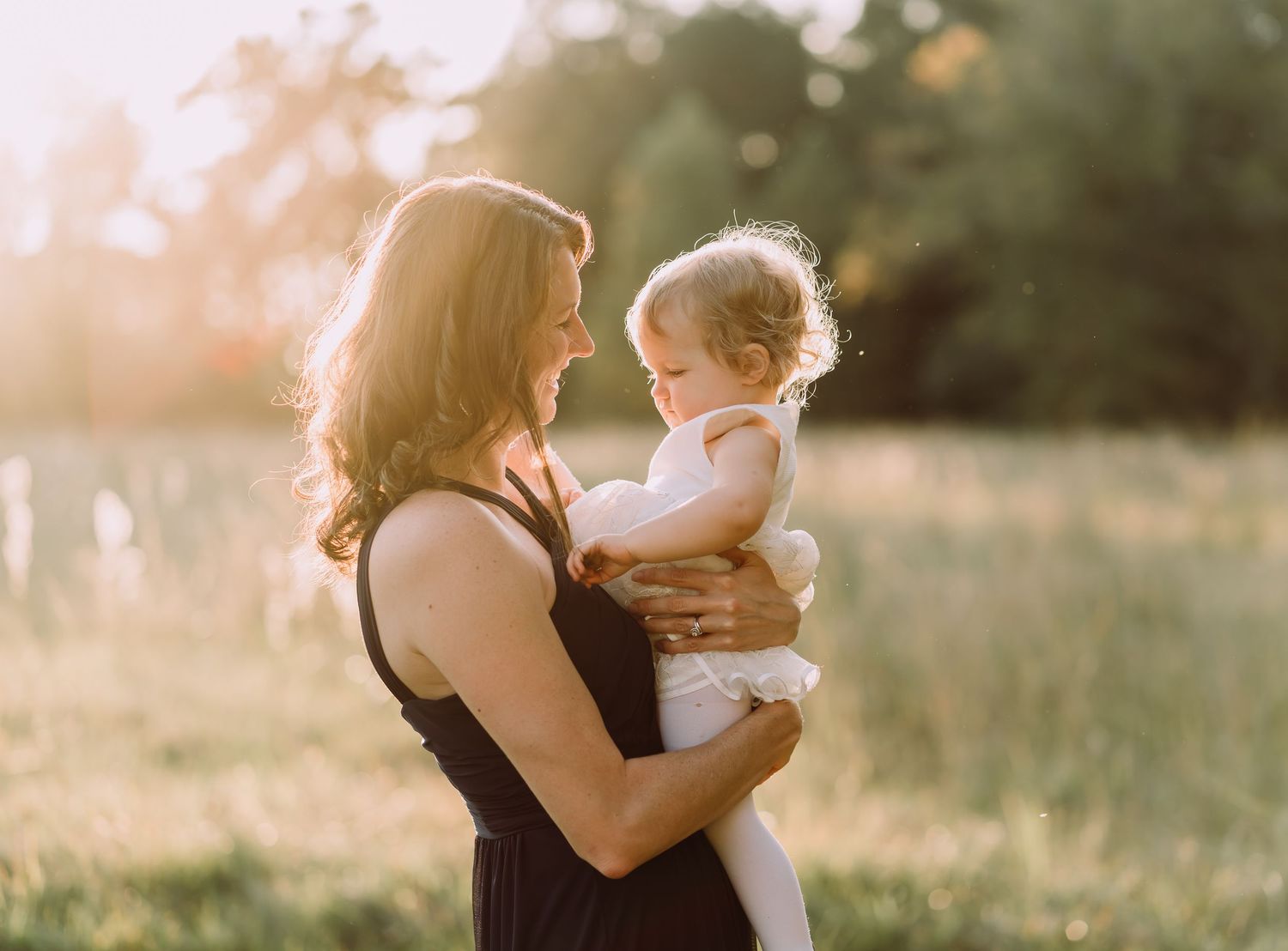 Tender sunset moment shared between parent and child in a golden-lit field.