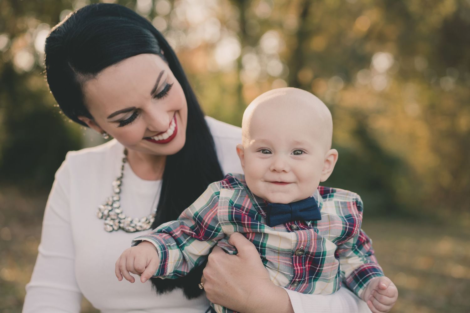 Joyful winter portrait featuring baby in plaid and parent in white.