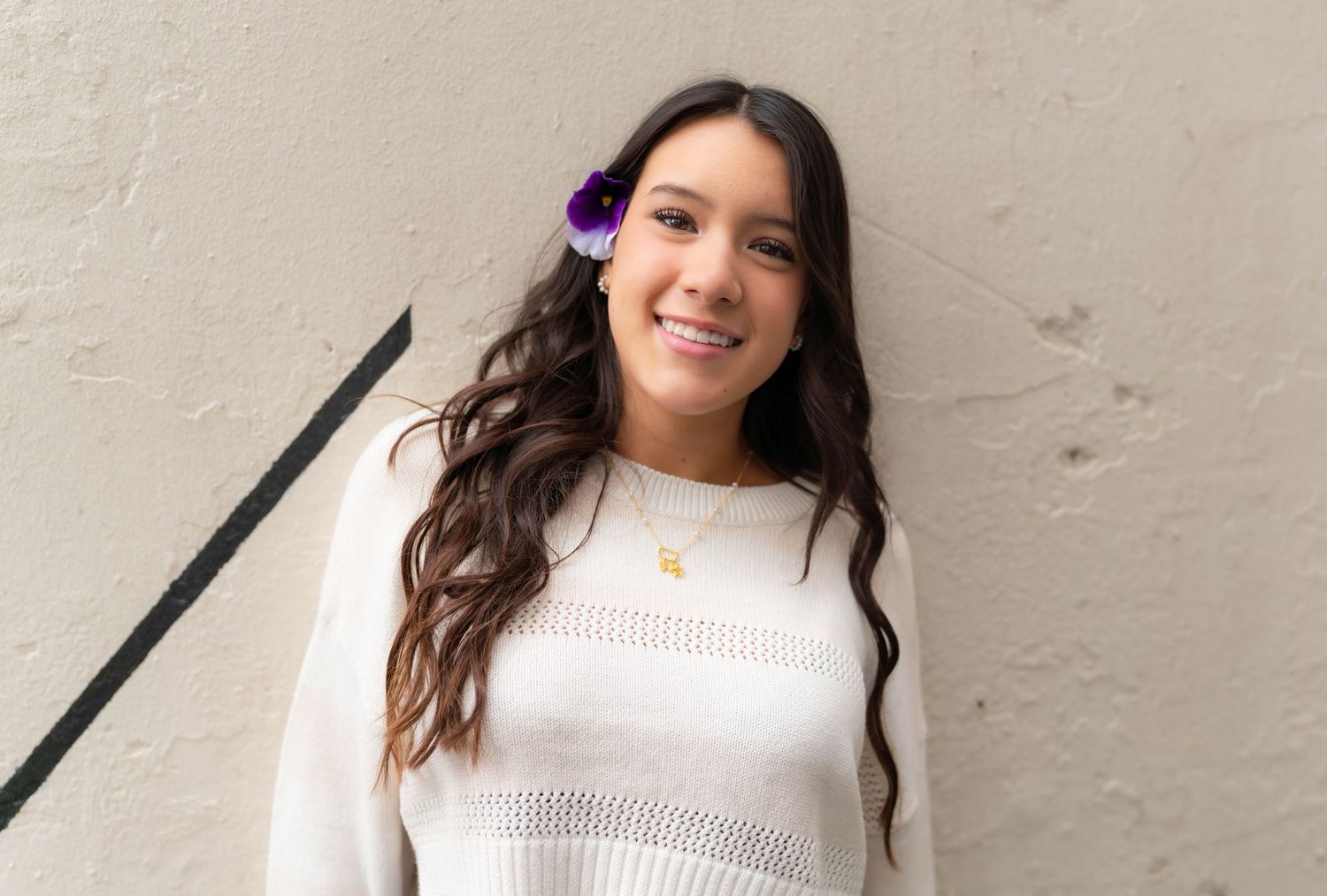 A woman in a white sweater poses against a light-colored wall in a series of four similar photos.