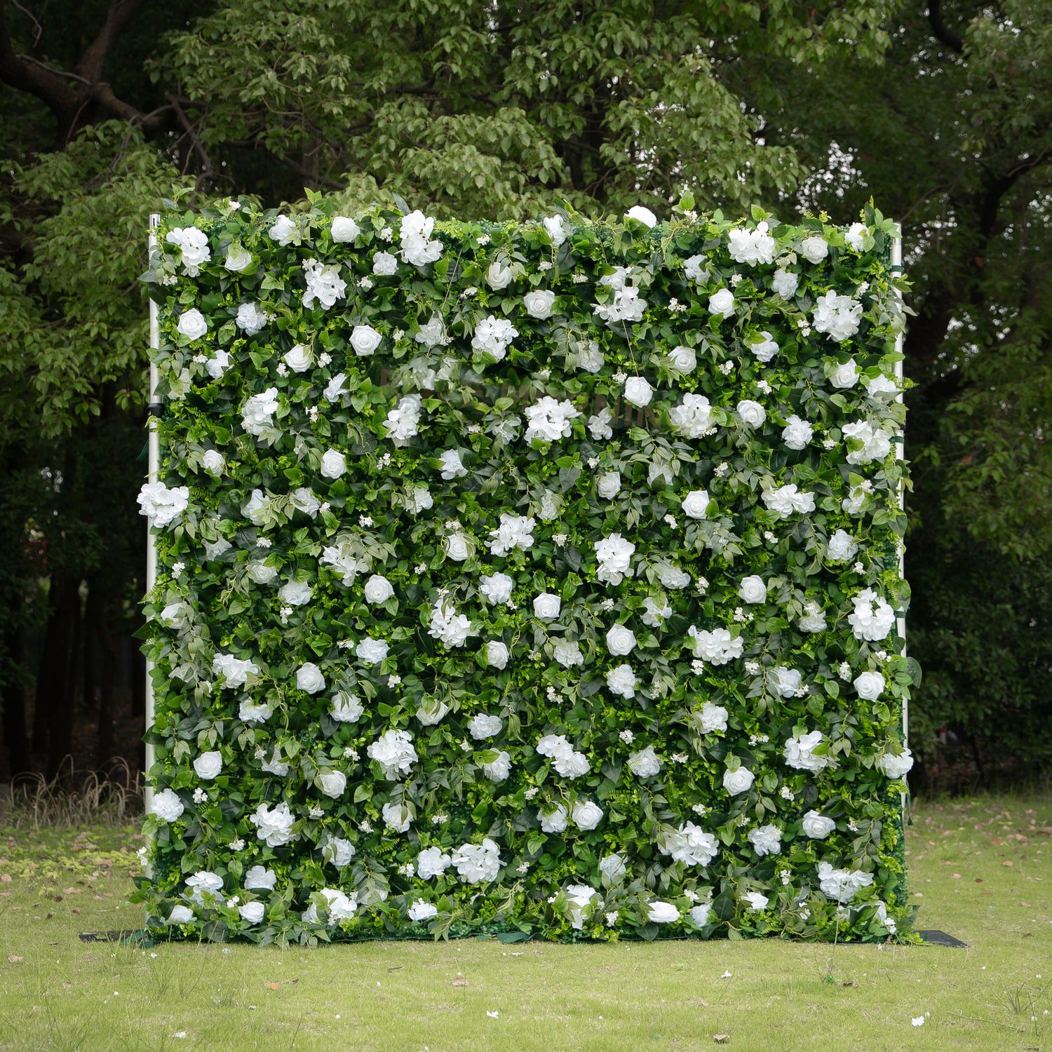 White floral backdrop with green foliage perfect for outdoor wedding photography.
