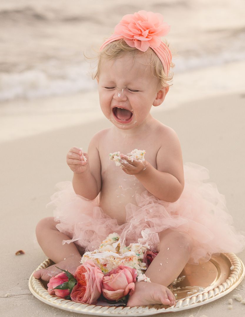 Laughing baby in pink tutu during beach cake smash photography session.