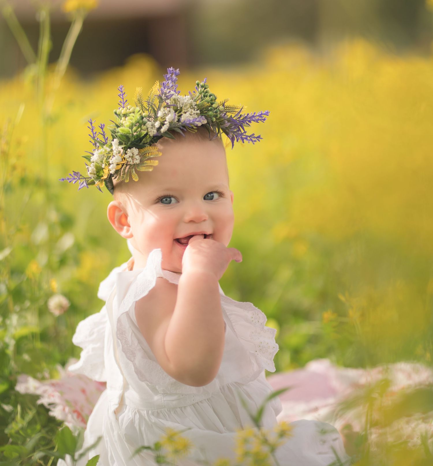 Sweet summer portrait of a baby wearing a flower crown in a field of yellow wildflowers.