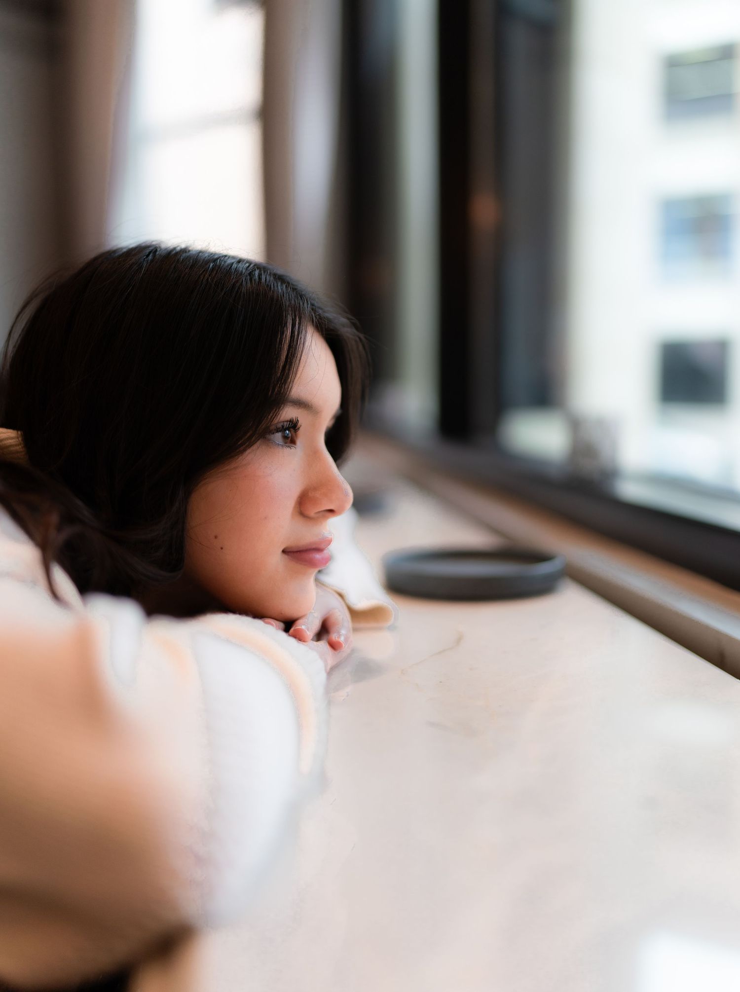 A person gazes thoughtfully through a window in a series of similar profile shots with soft natural lighting.