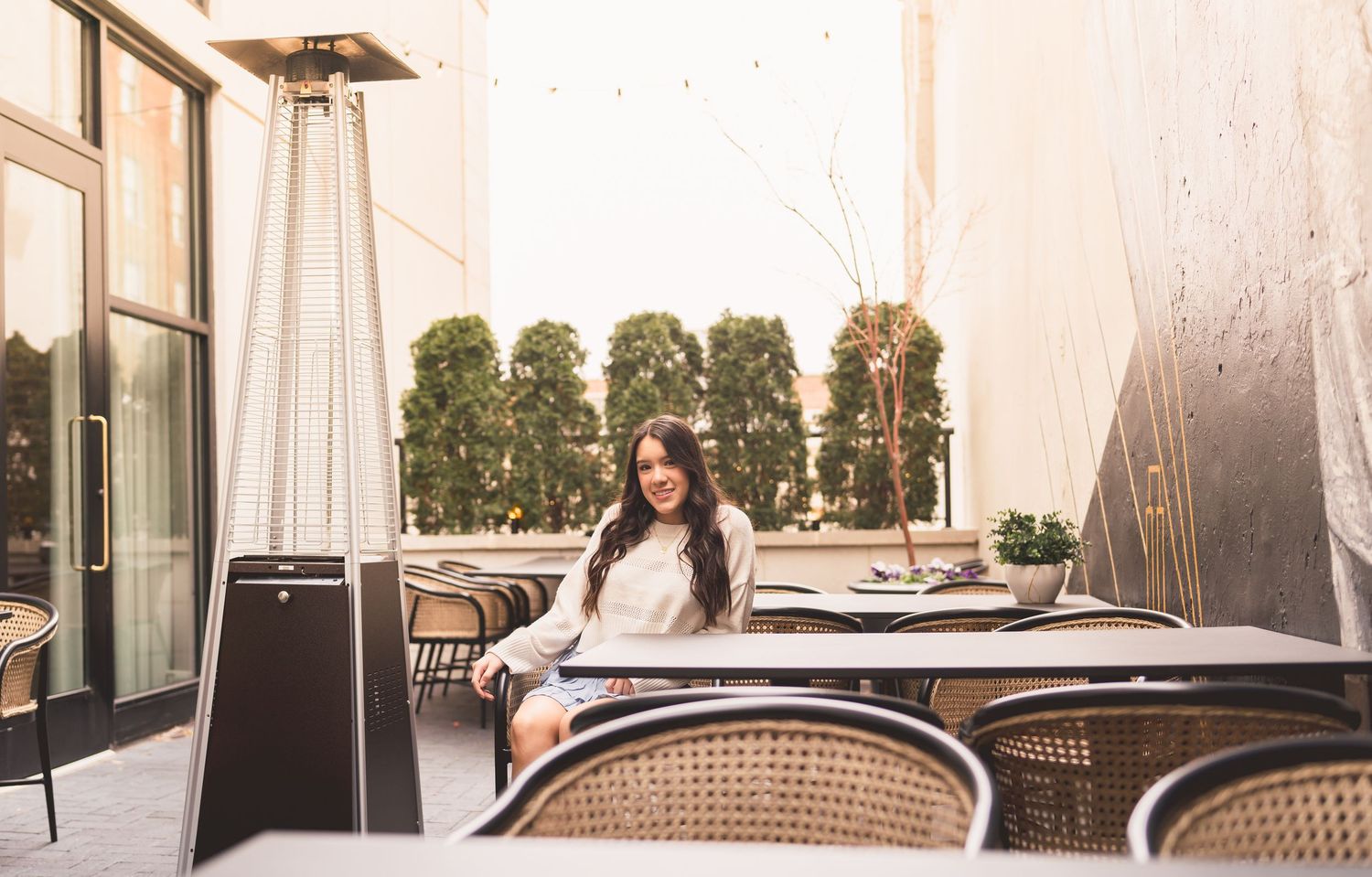 Outdoor patio seating area with rattan chairs and tables arranged along a modern building exterior.