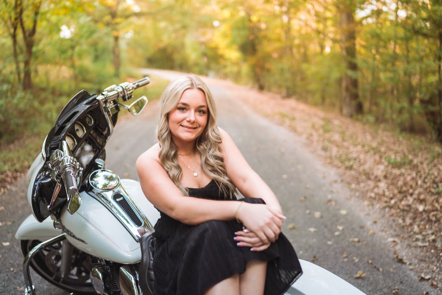 A motorcycle is parked on an autumn path surrounded by golden trees and fallen leaves.