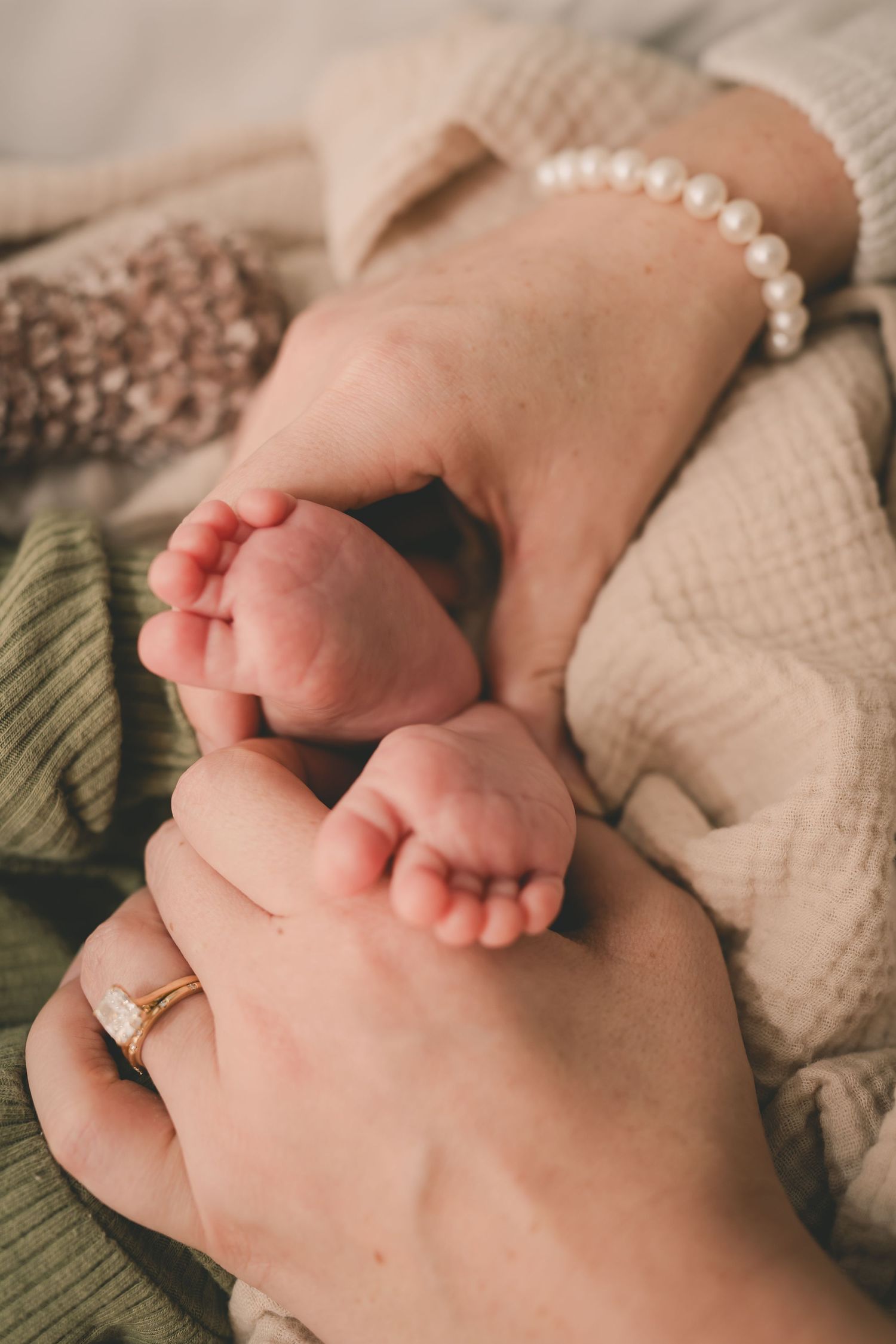 Close-up series of tiny newborn baby feet with mother's hands wearing pearl bracelet.