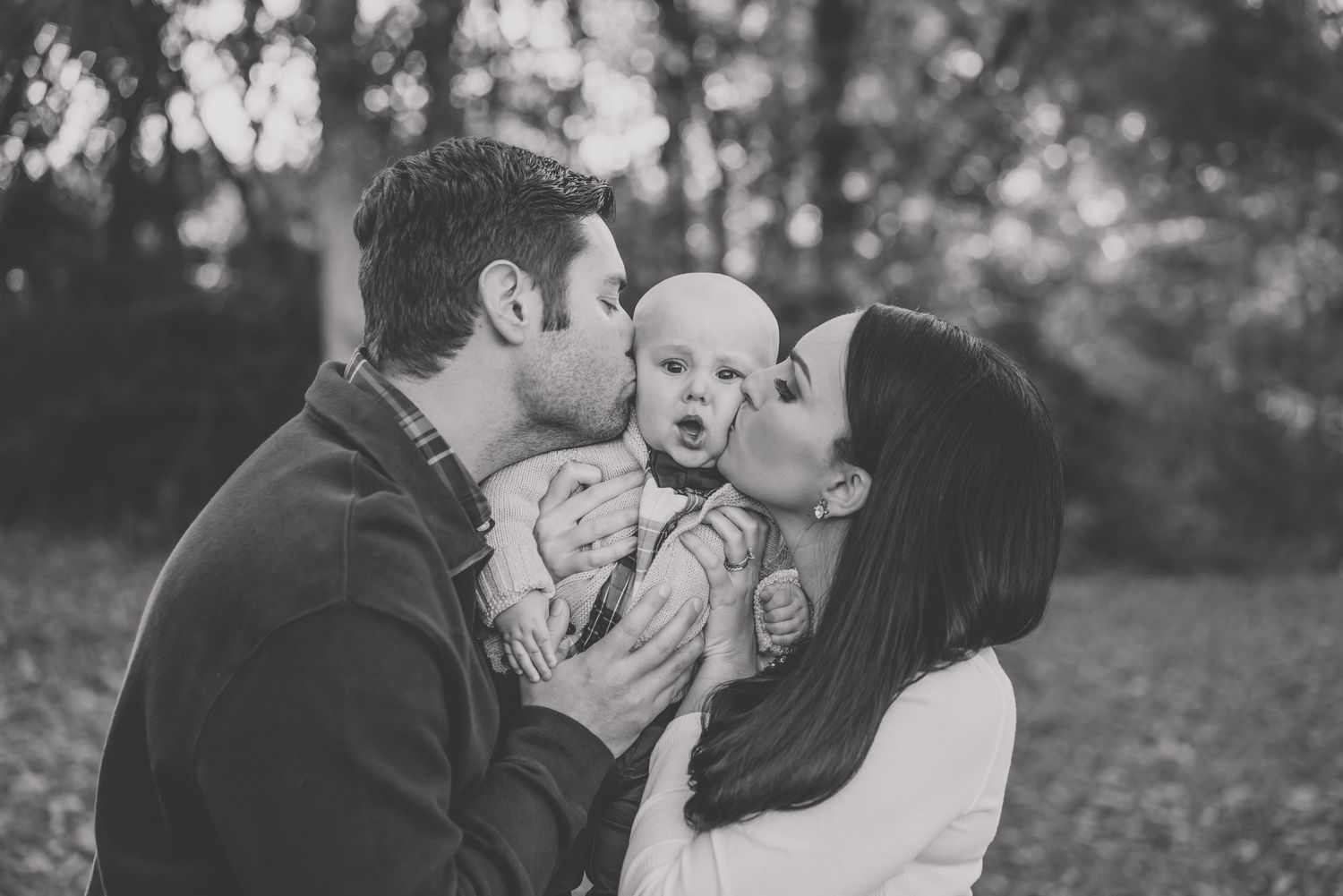 Black and white intimate family moment with baby outdoors.