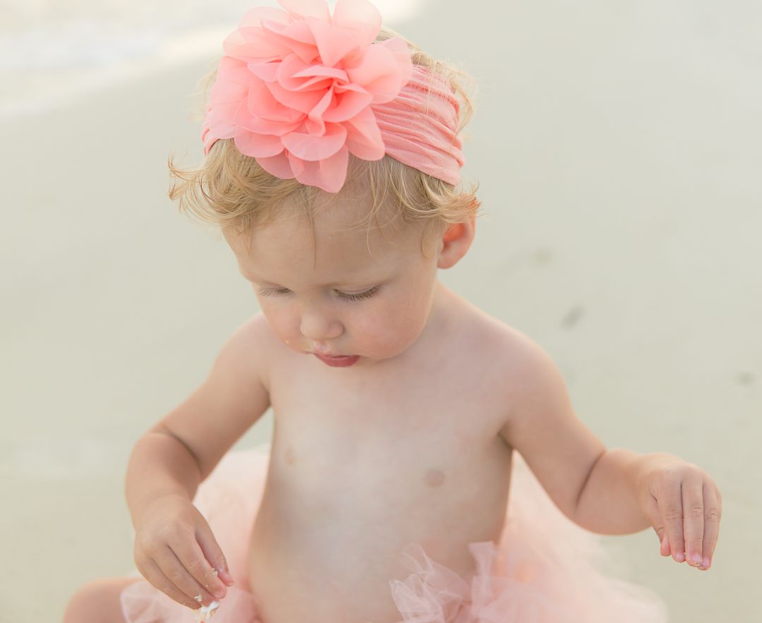 Small child wearing pink tulle tutu and floral headpiece during outdoor photoshoot.