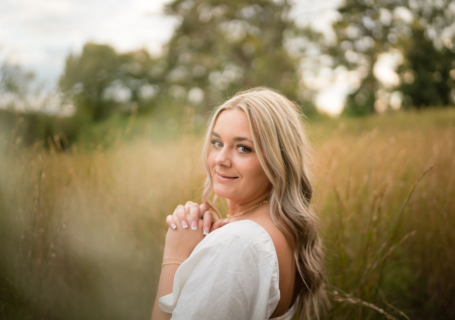 A dreamy outdoor portrait session in a golden field at sunset with soft natural lighting and bokeh effects.