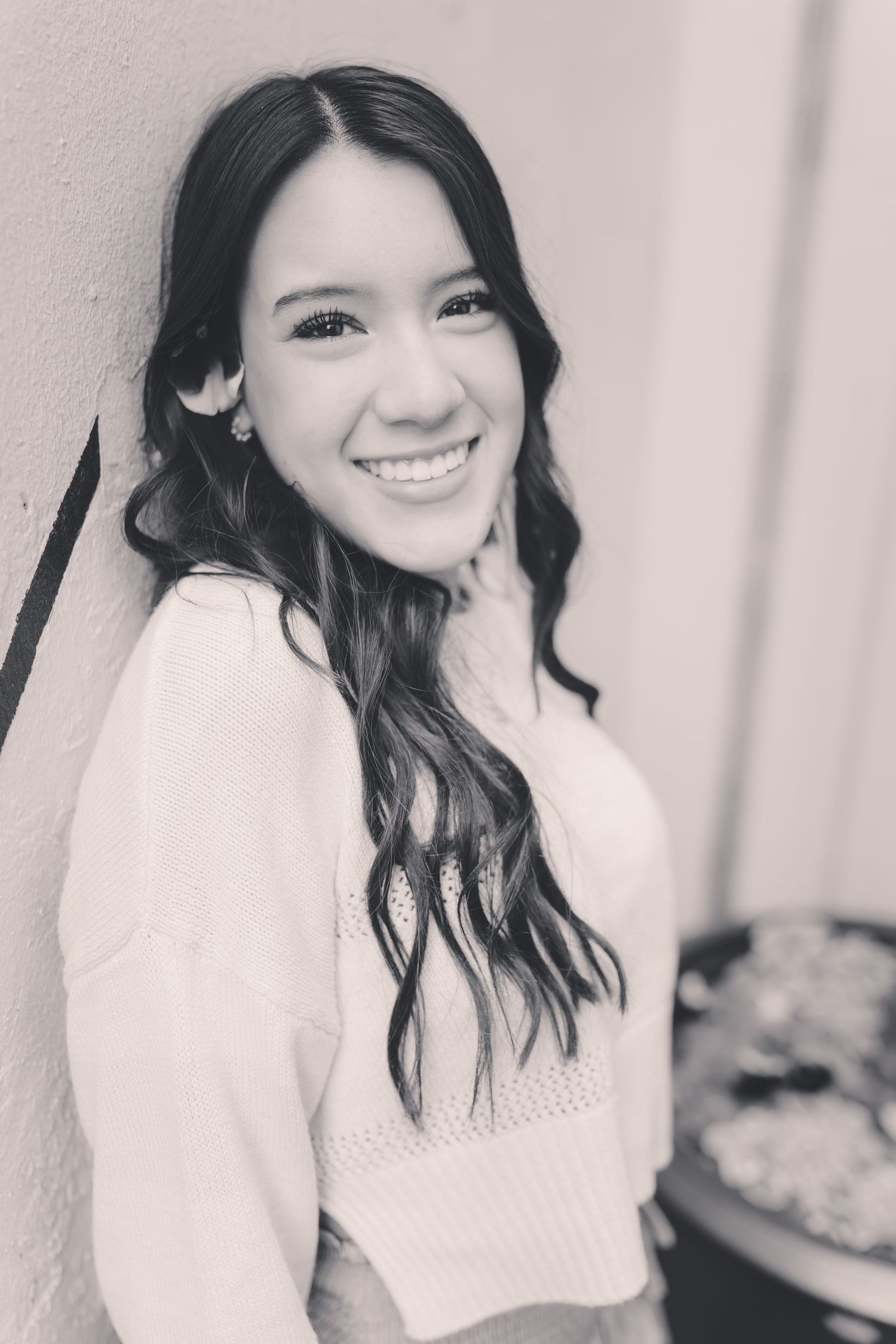 A series of black and white portraits showing someone with dark wavy hair wearing a white sweater against a light background.