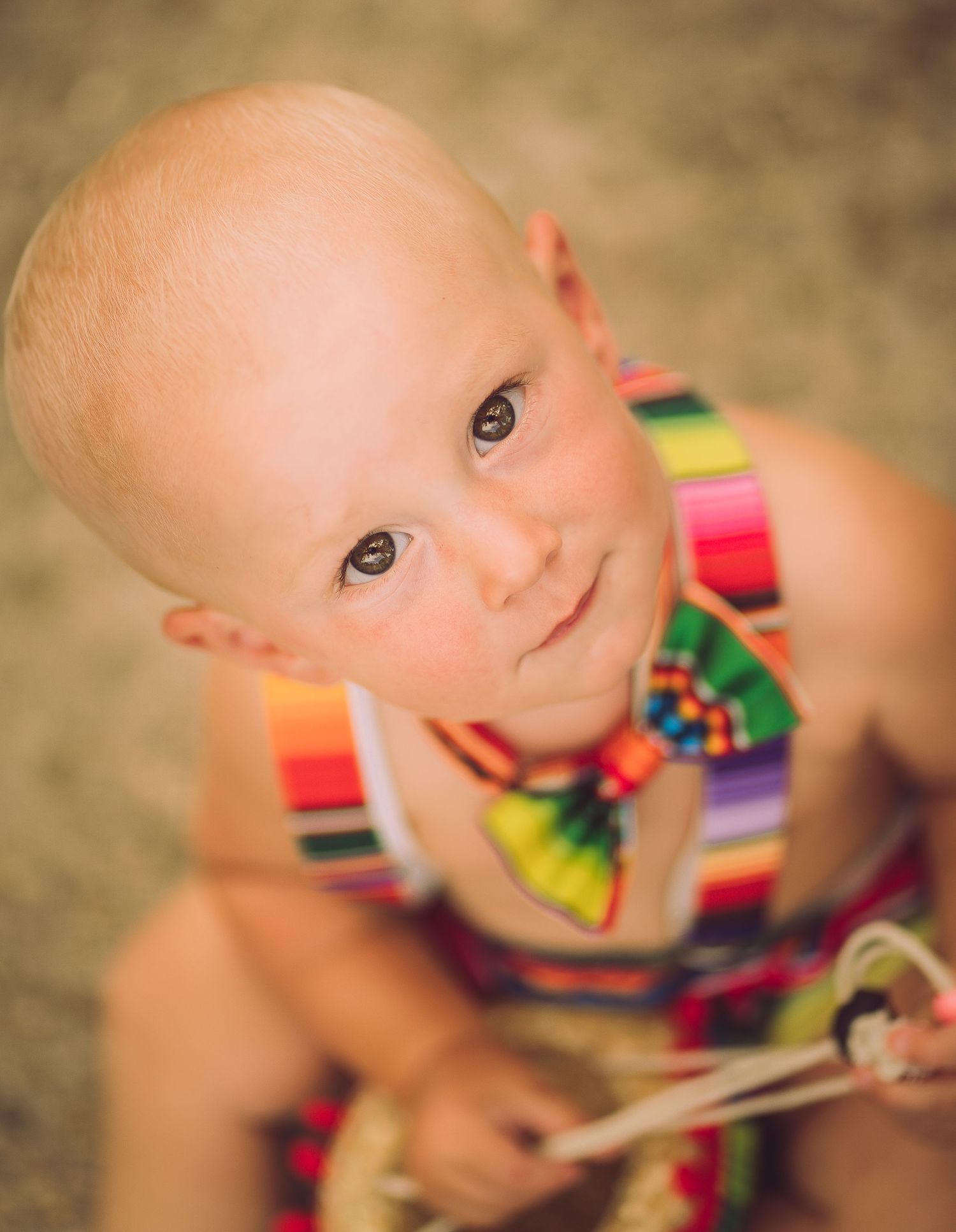 Close up of baby wearing colorful rainbow striped outfit looking at camera.
