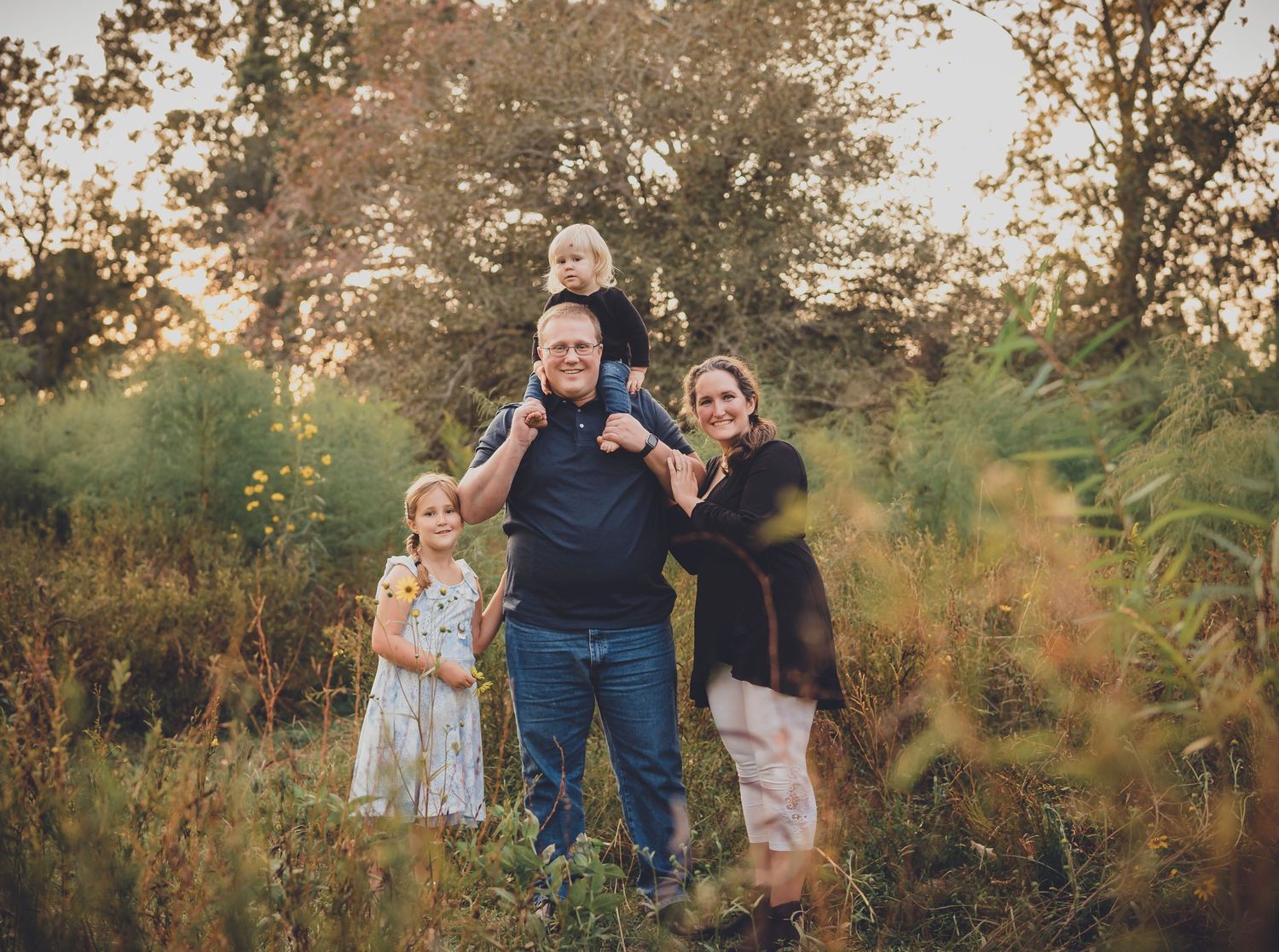 Family enjoying golden hour photography session in a wildflower meadow during sunset.
