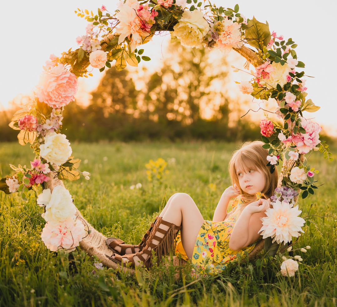 Dreamy portrait under floral arch with pink and peach blooms at sunset.