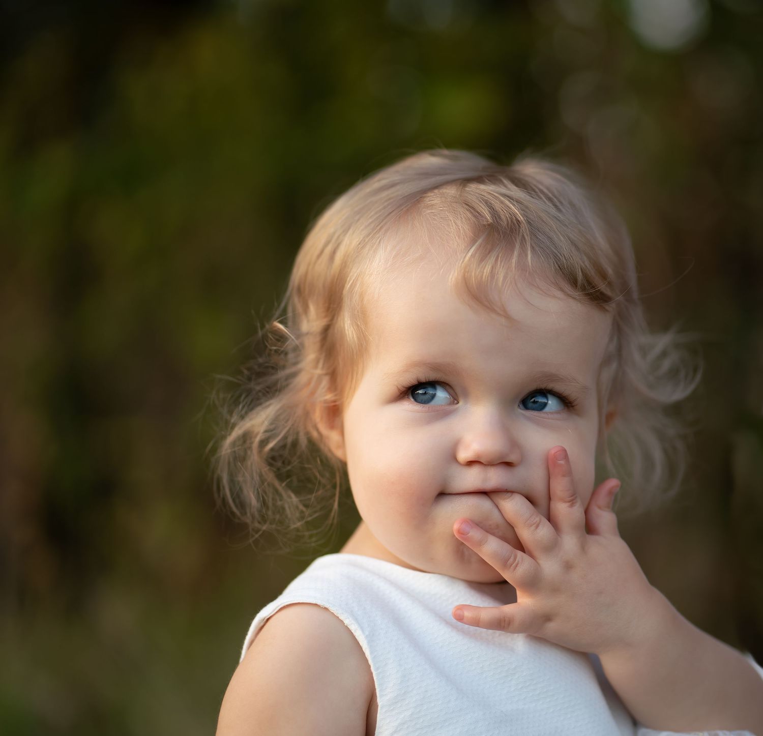 Close-up portrait of toddler with blonde curls and bright blue eyes.