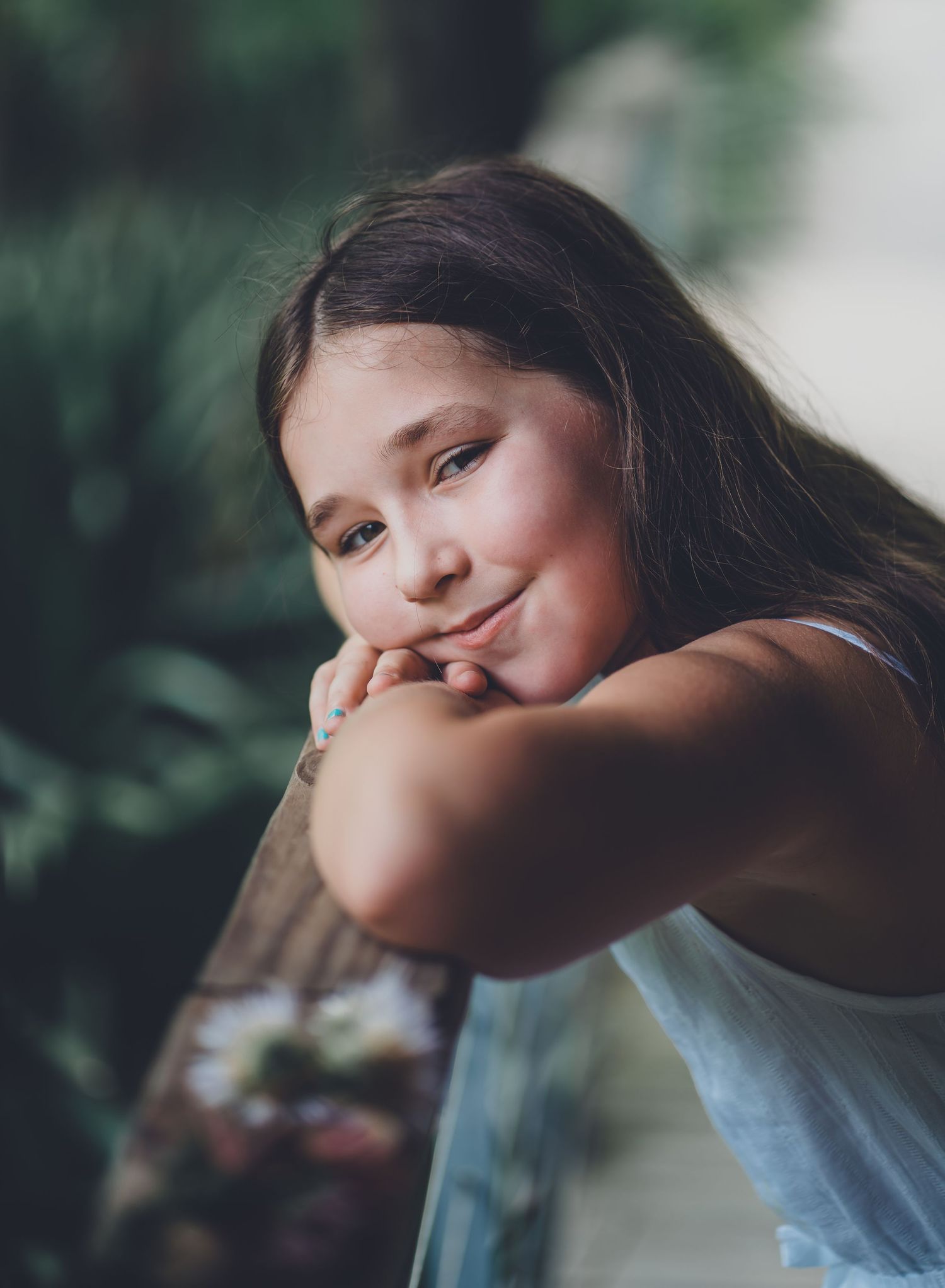 Close up portrait of young girl resting head on arms with dreamy expression.