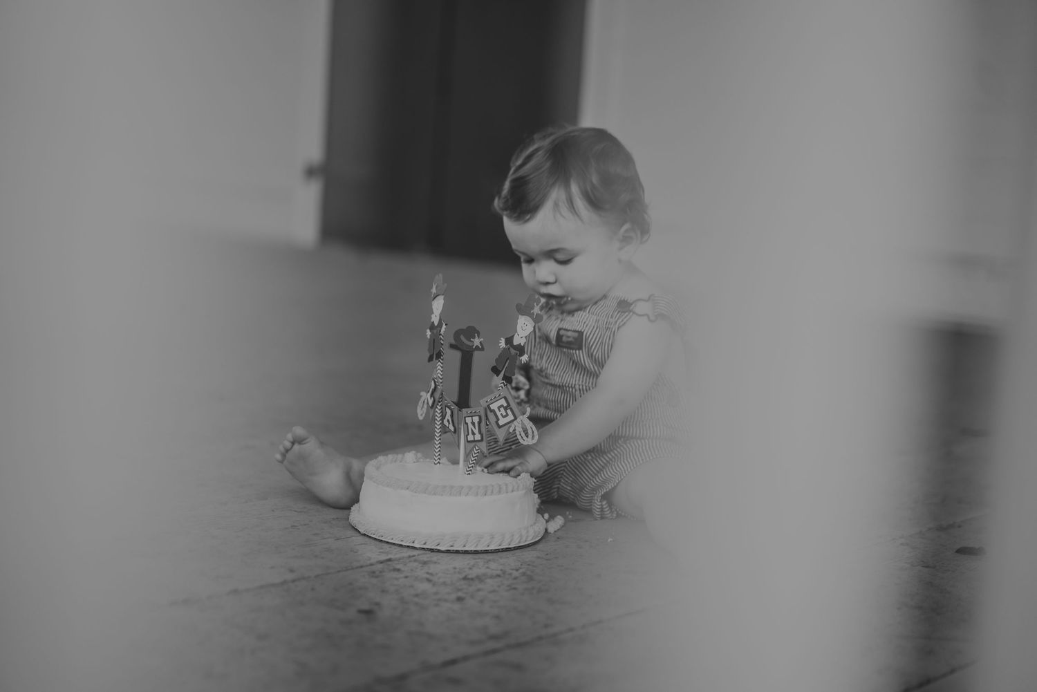 Black and white photo of baby sitting with birthday cake.