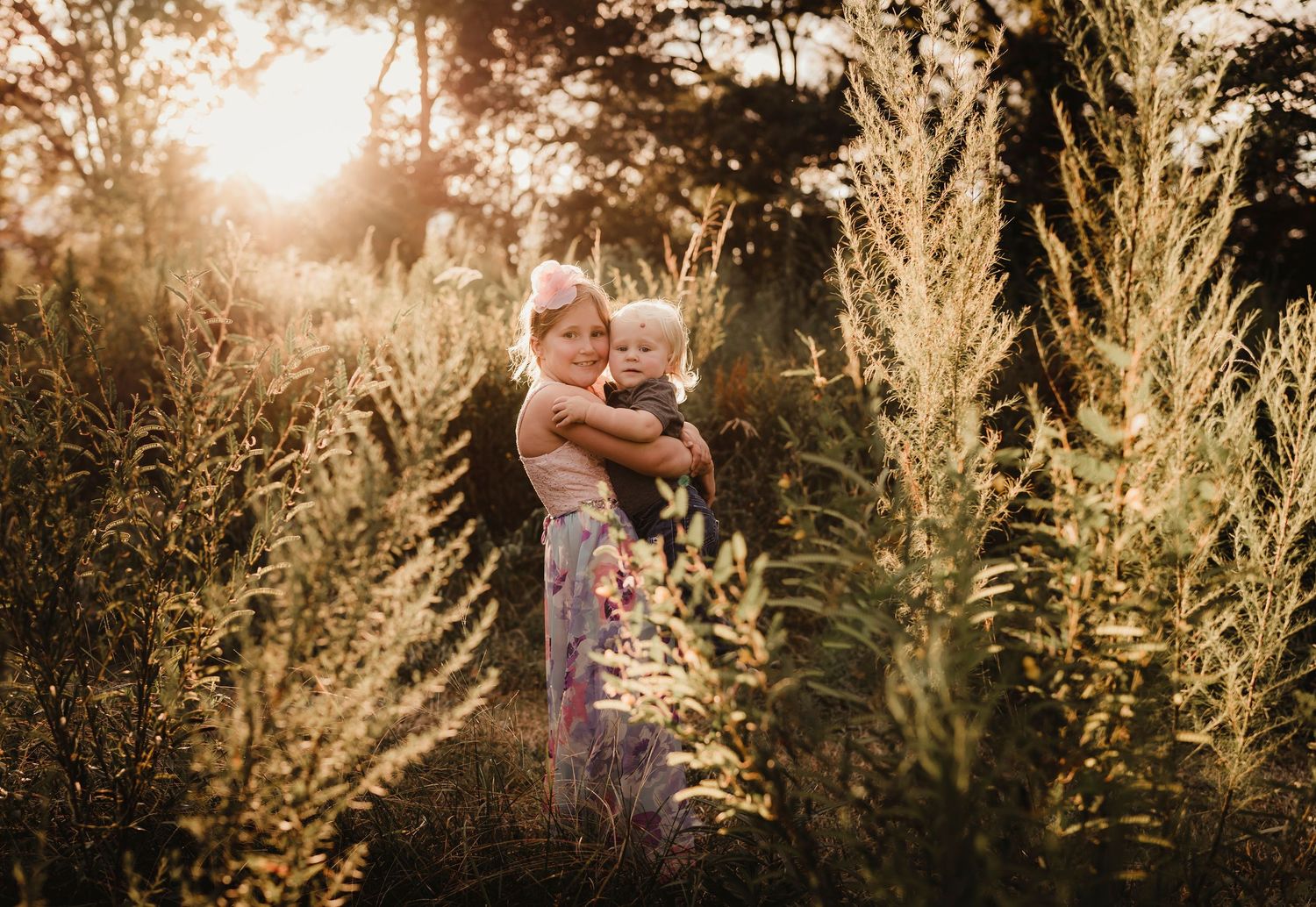Silhouette of figures in tall grass during golden sunset.