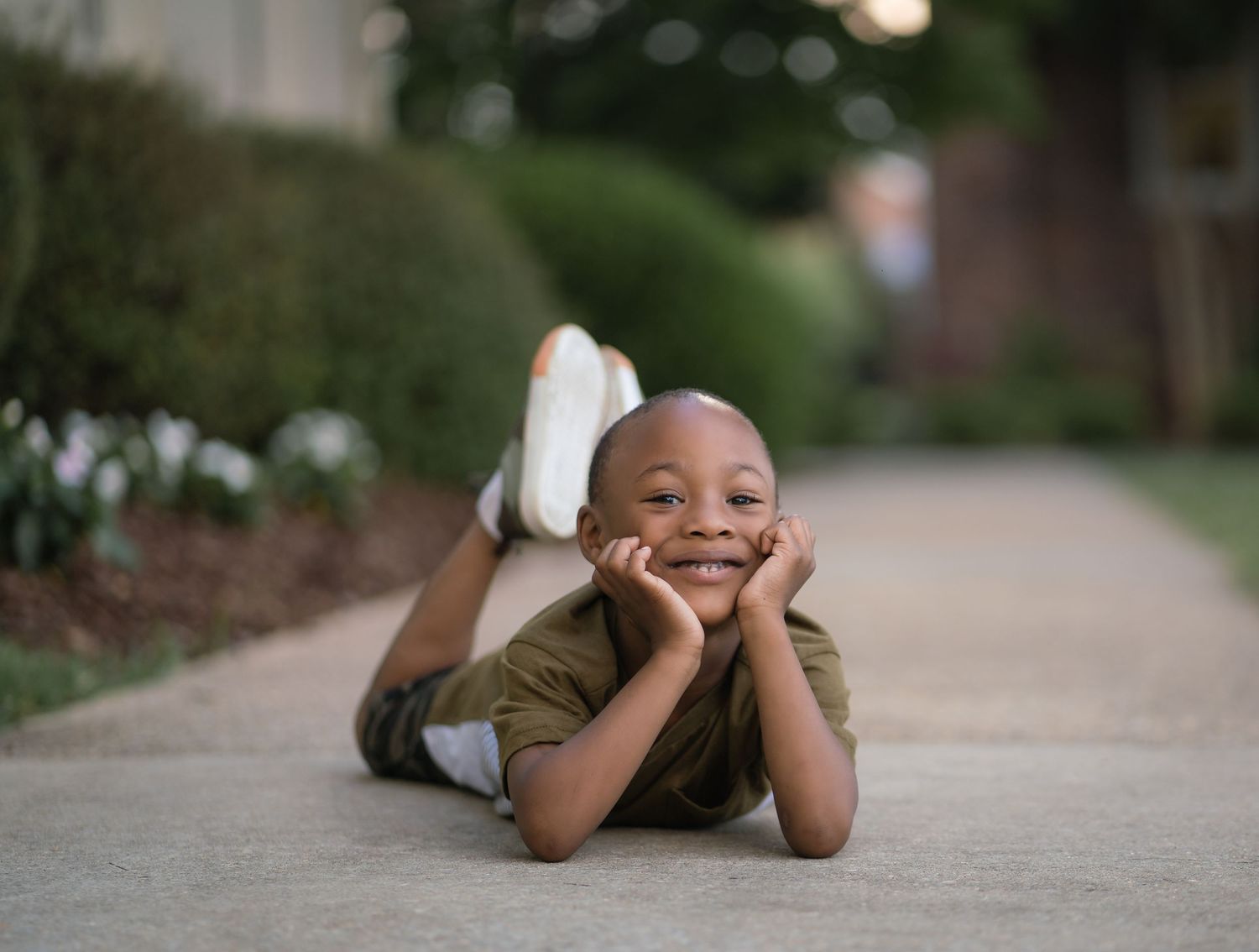 A person lying on a concrete path with feet raised in a playful pose outdoors.