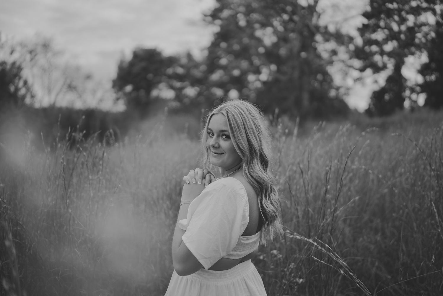Black and white outdoor portraits showing a person posing in a field with dramatic lighting and natural scenery.